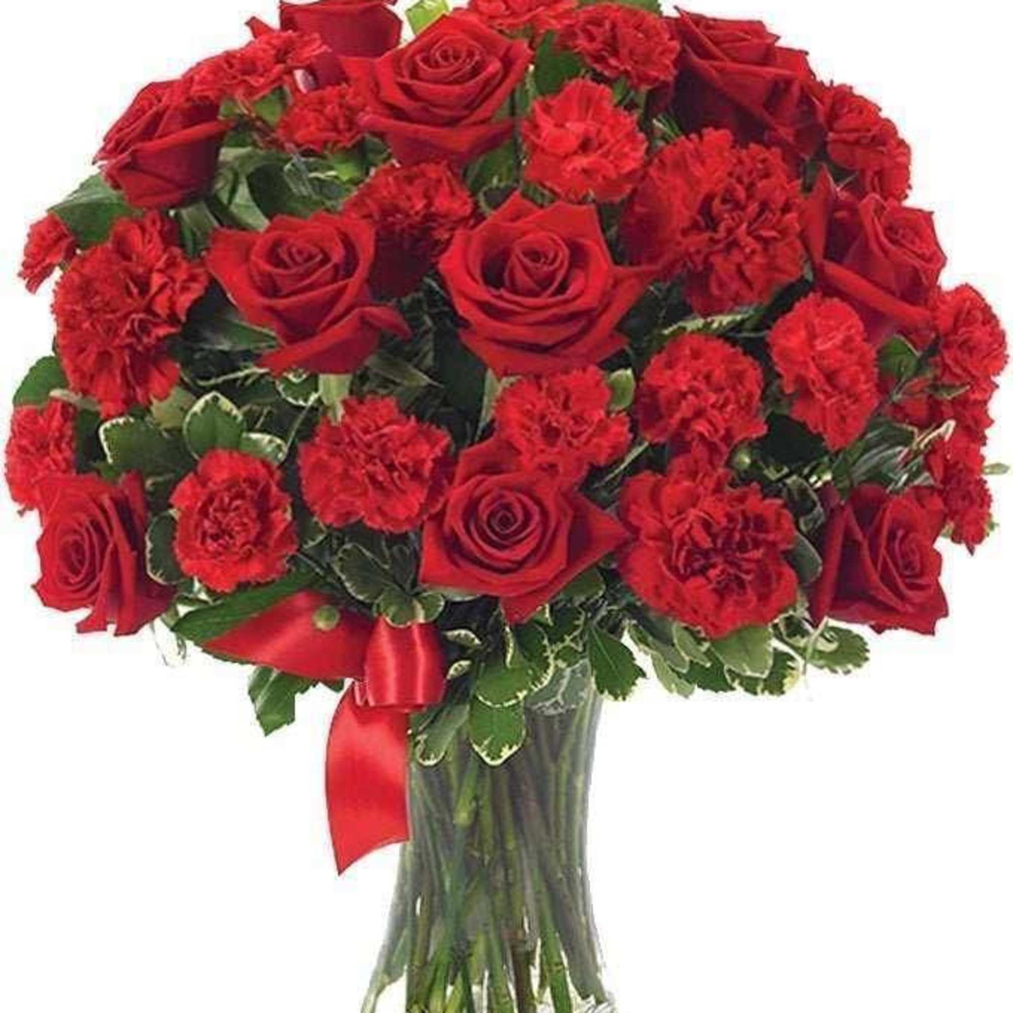 Red roses and carnations in a clear glass vase with a red ribbon