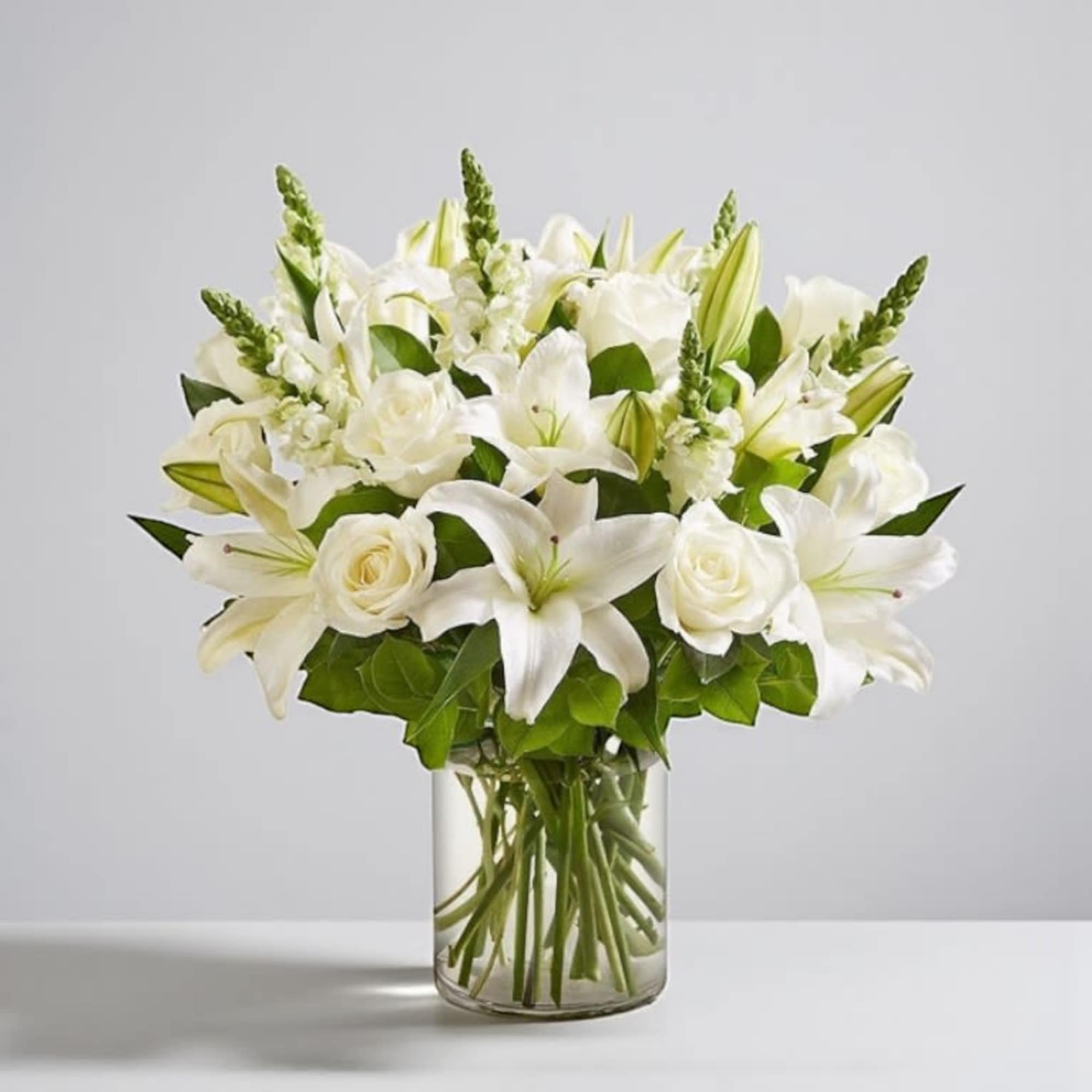White lilies and roses arranged in a clear glass vase