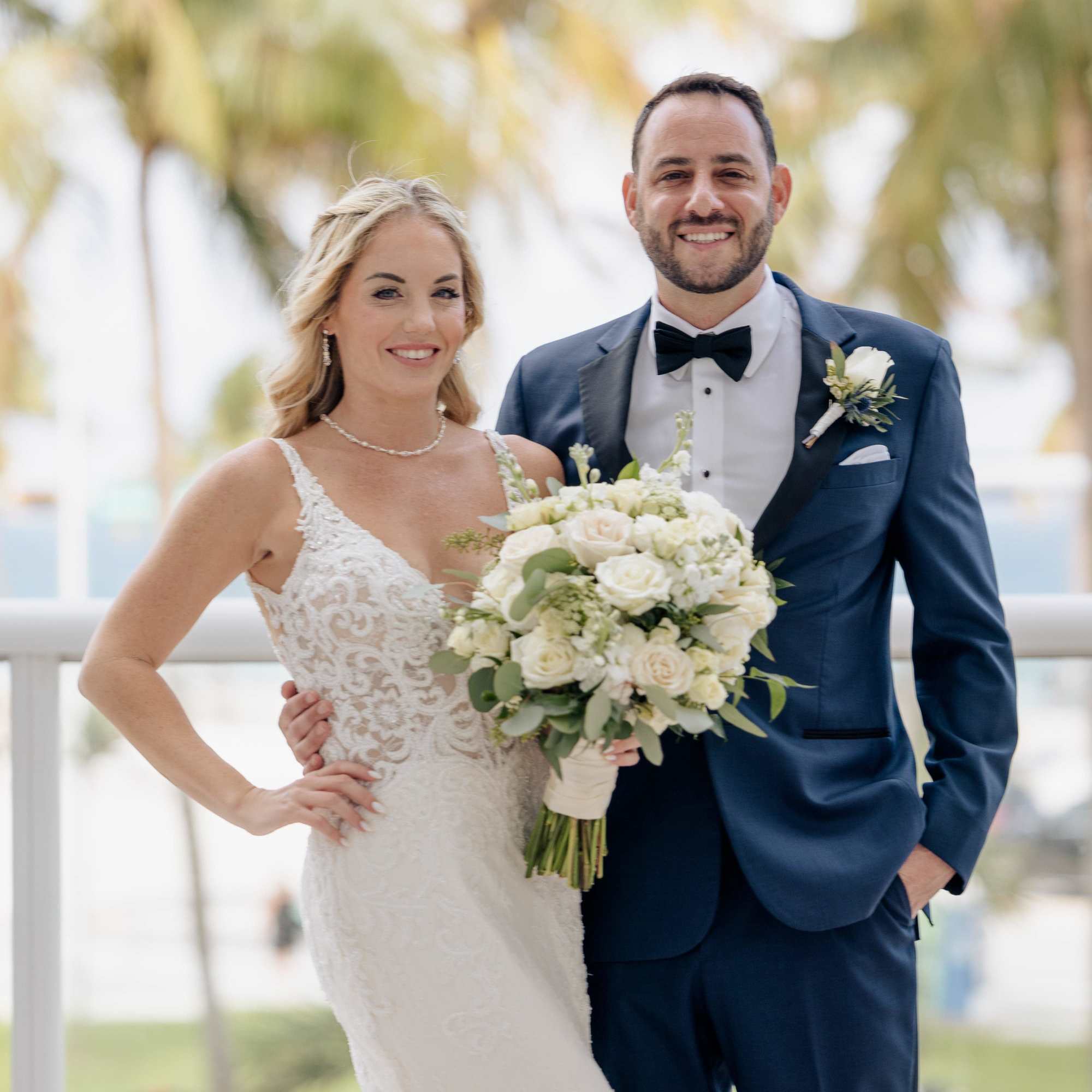 Bride and groom holding a white rose bouquet