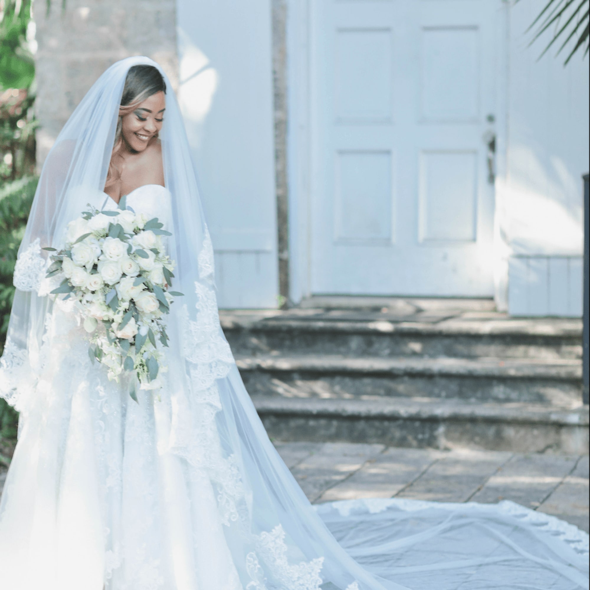 Bride holding a white rose bouquet with greenery