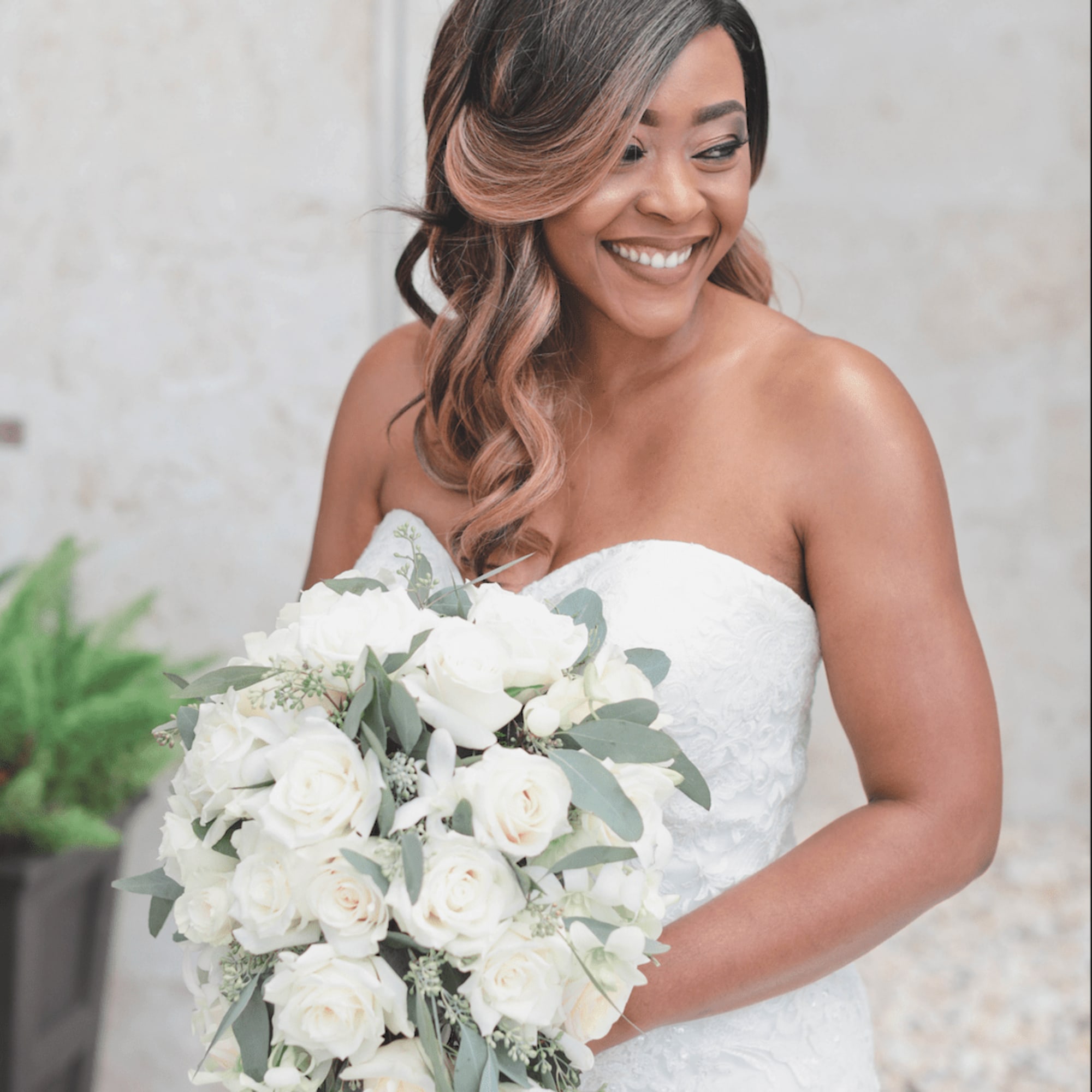 Bride holding a cascading bouquet of white roses and greenery, photo 2 of 3