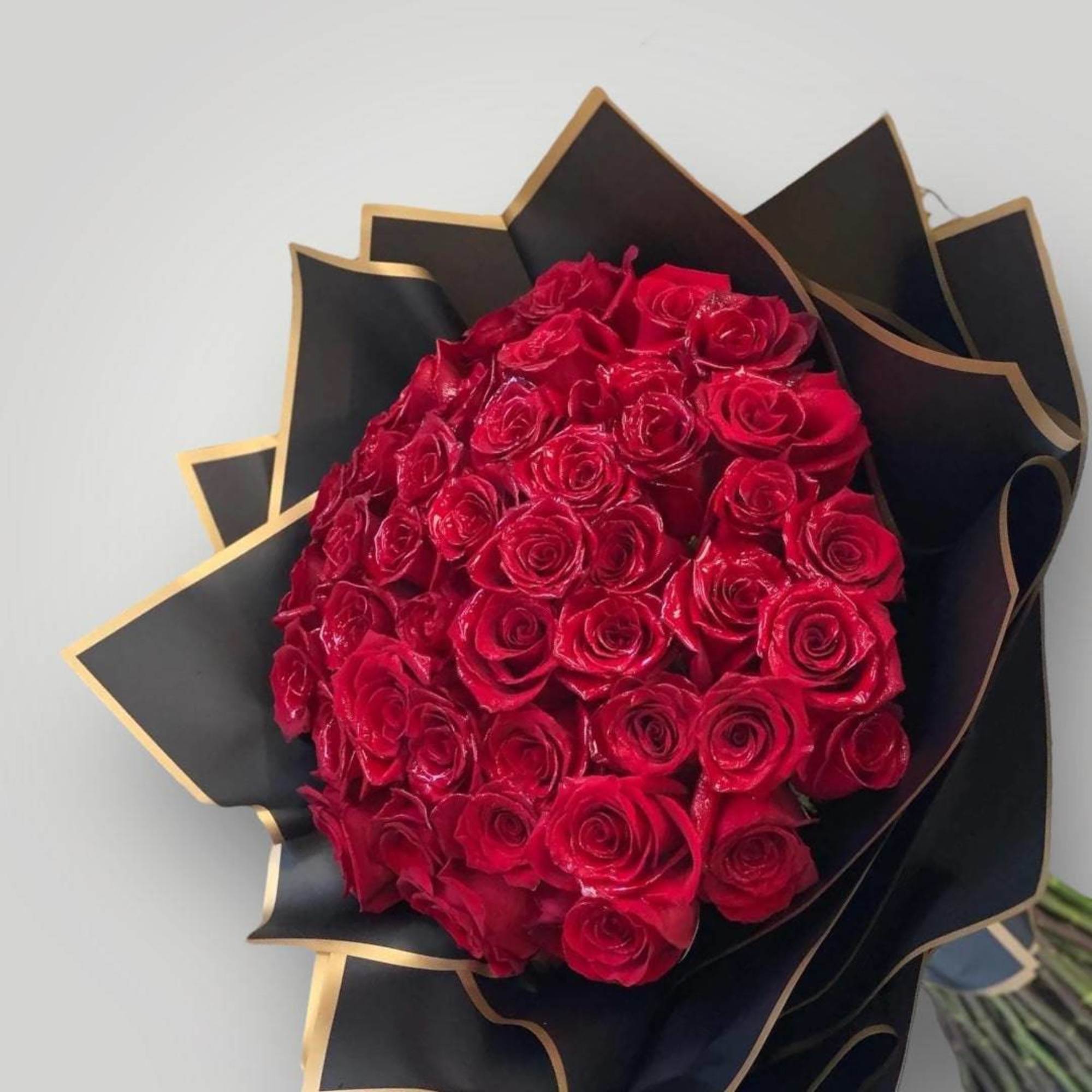 Bouquet of red roses wrapped in black paper with gold trim