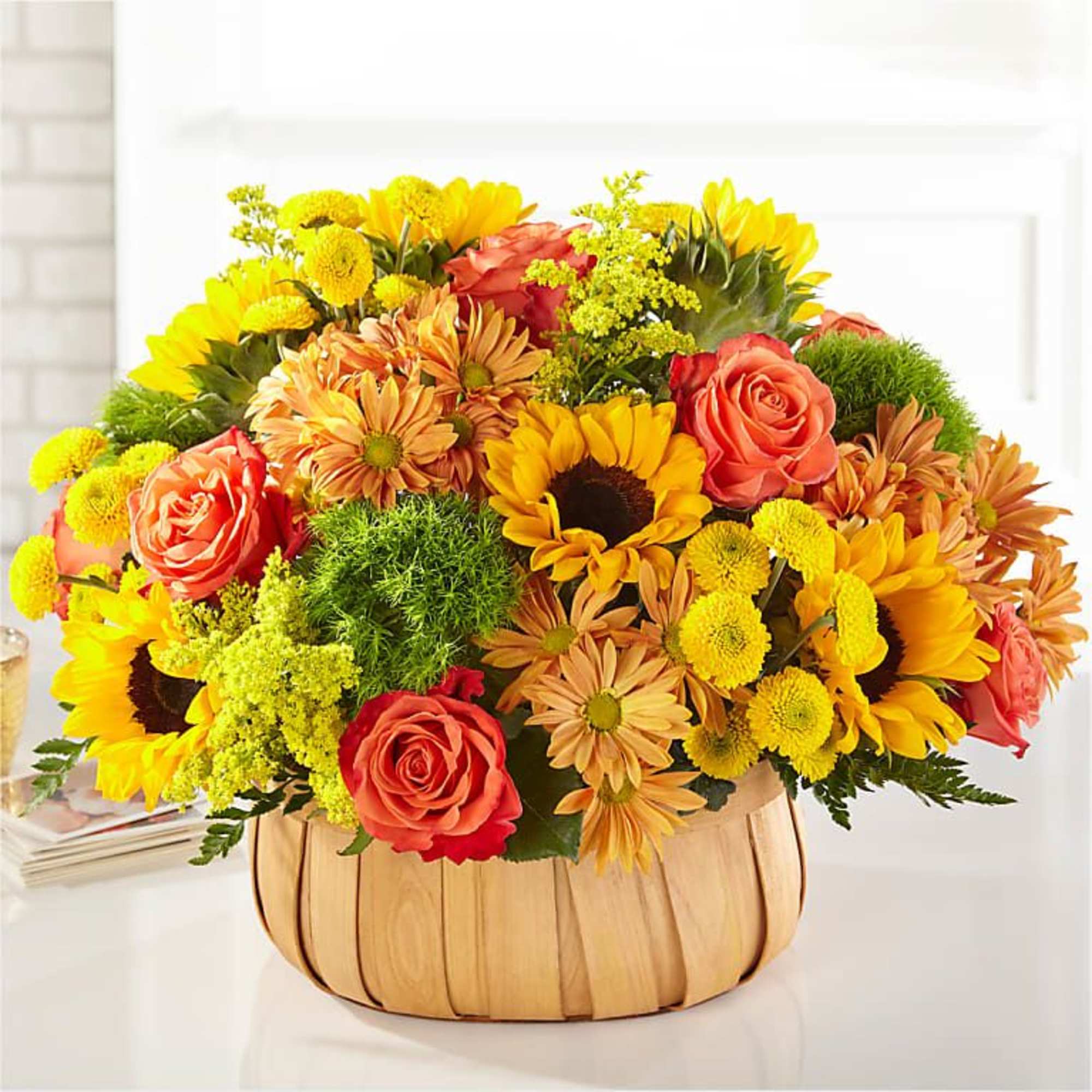 Mixed bouquet of sunflowers, roses, and daisies in a woven basket