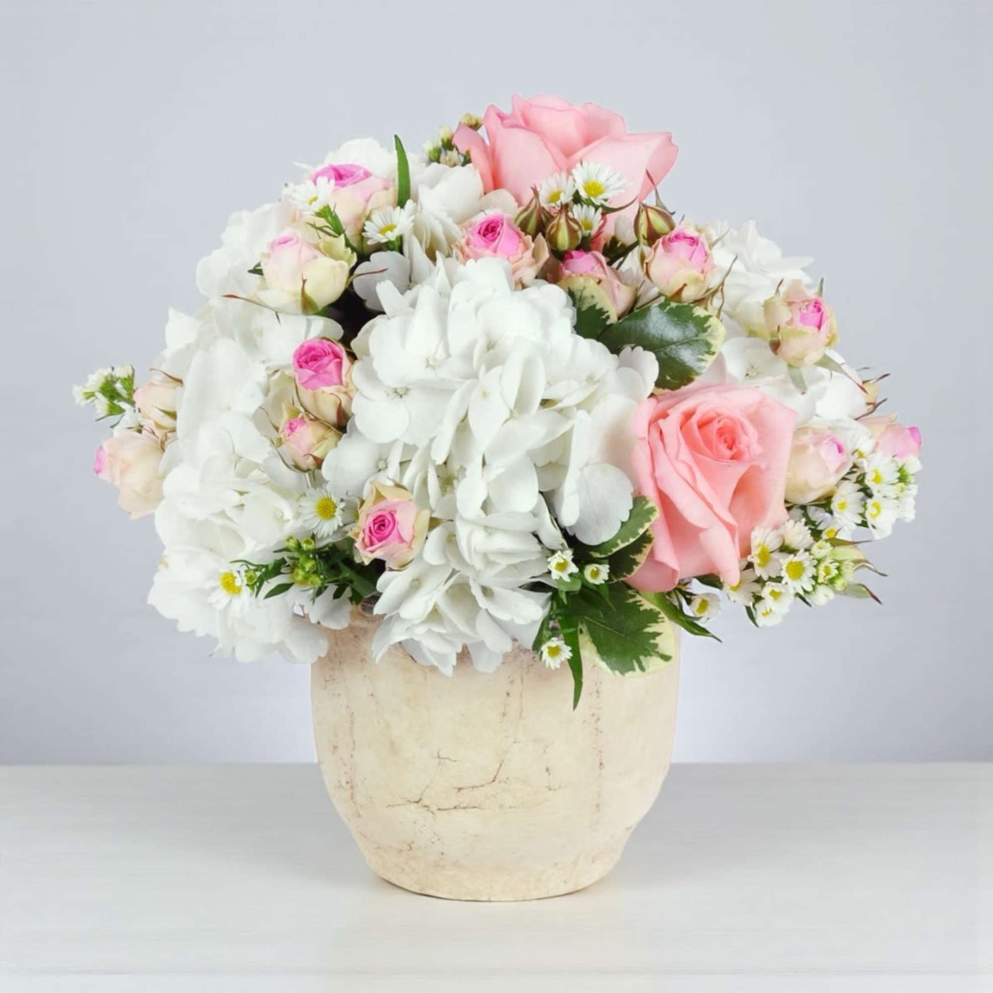Pink and white rose bouquet in a cream vase