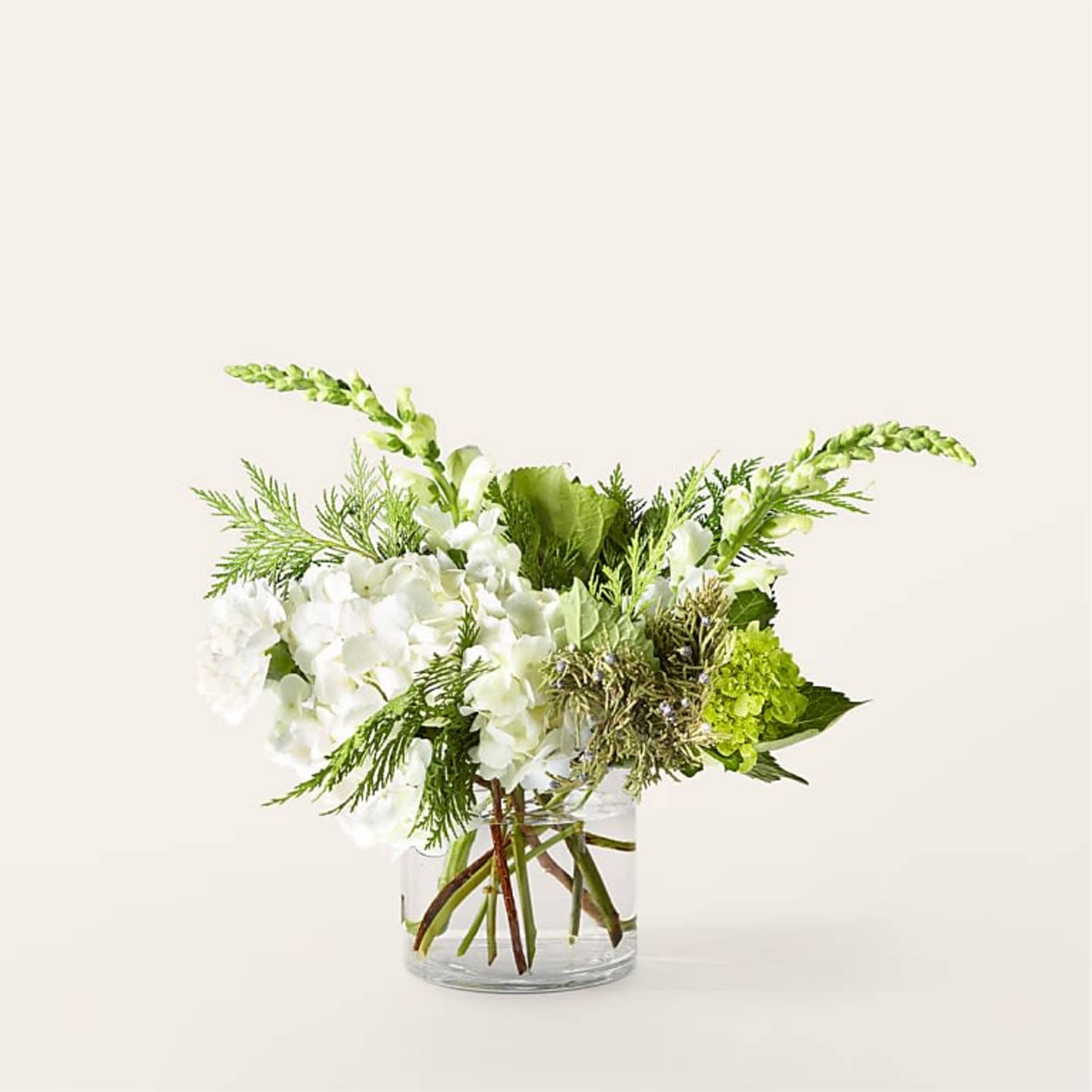 White flowers and green blooms arranged in a clear glass vase