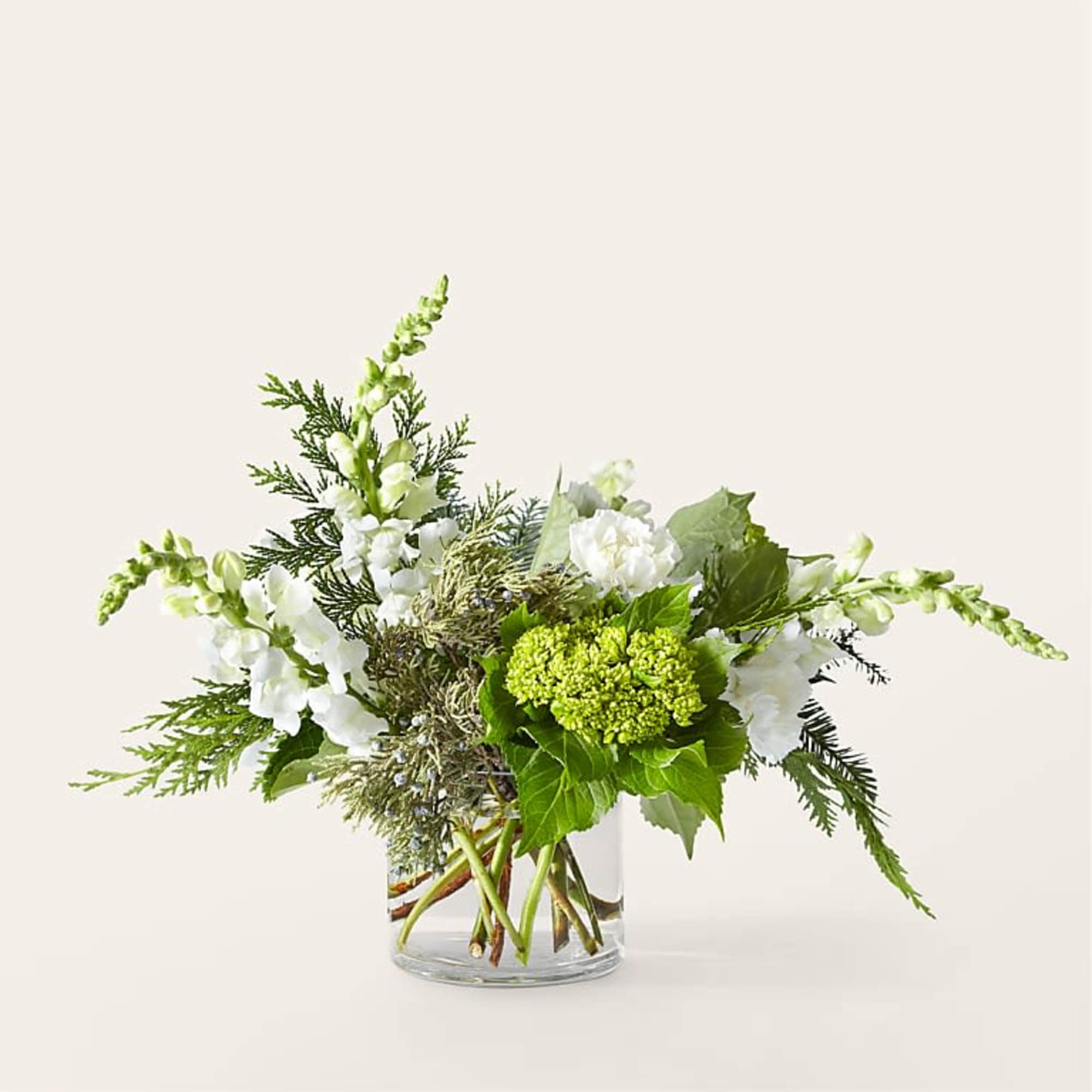 White flowers and green blooms arranged in a clear glass vase