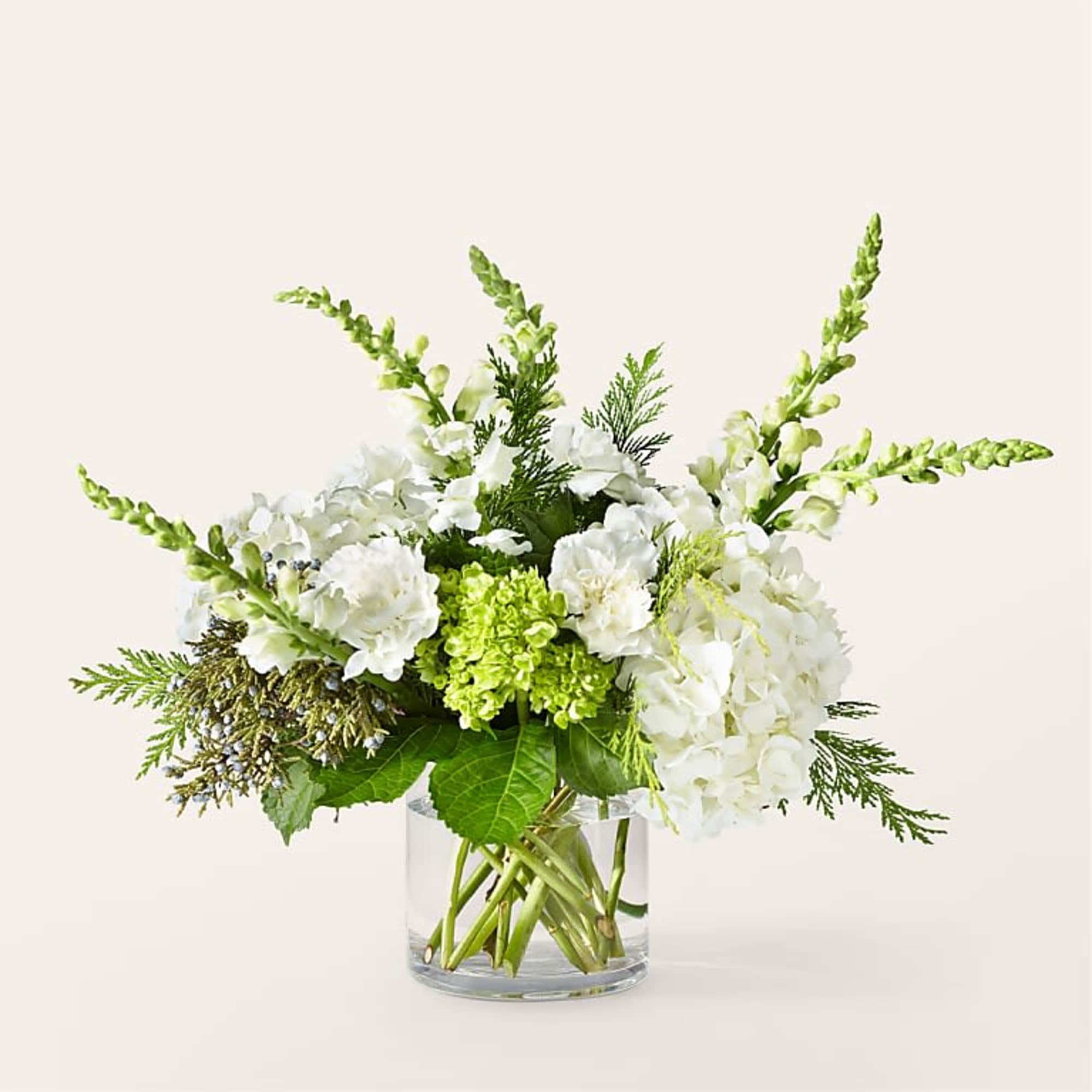 White flowers and green blooms arranged in a clear glass vase