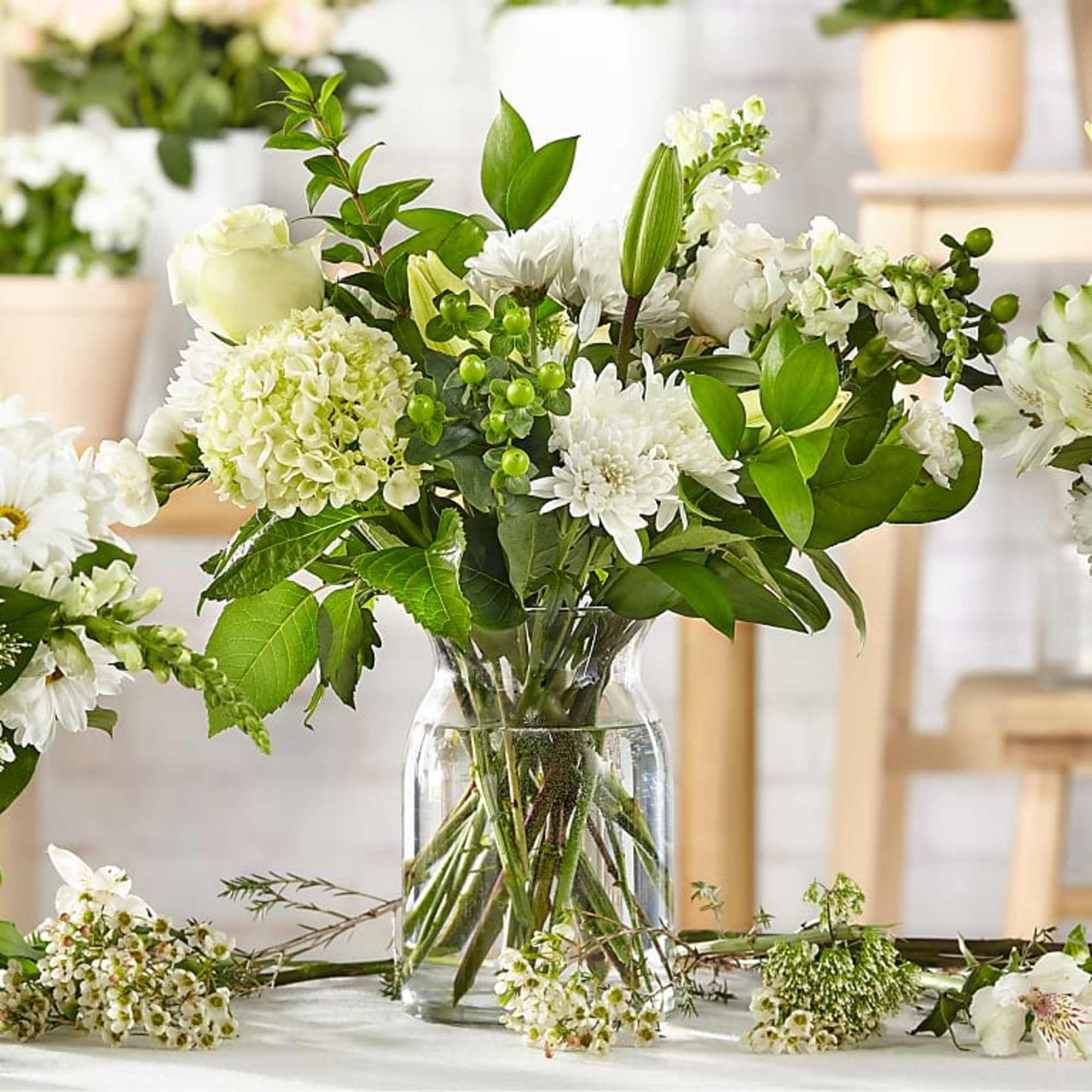 White flowers arranged in a clear glass vase with green foliage