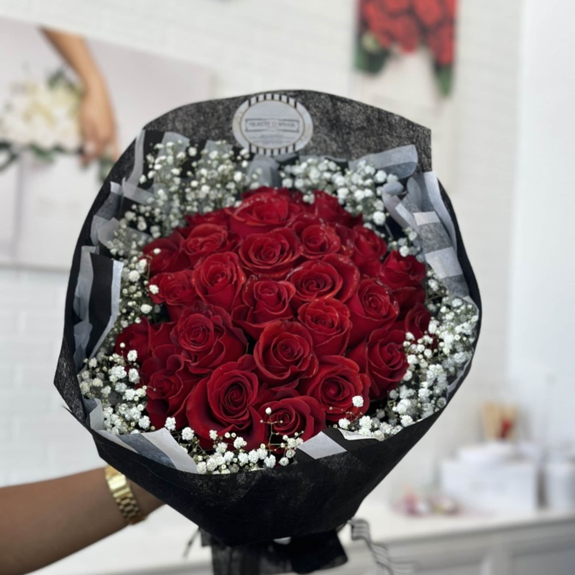 Bouquet of red roses with white baby's breath in black wrapping