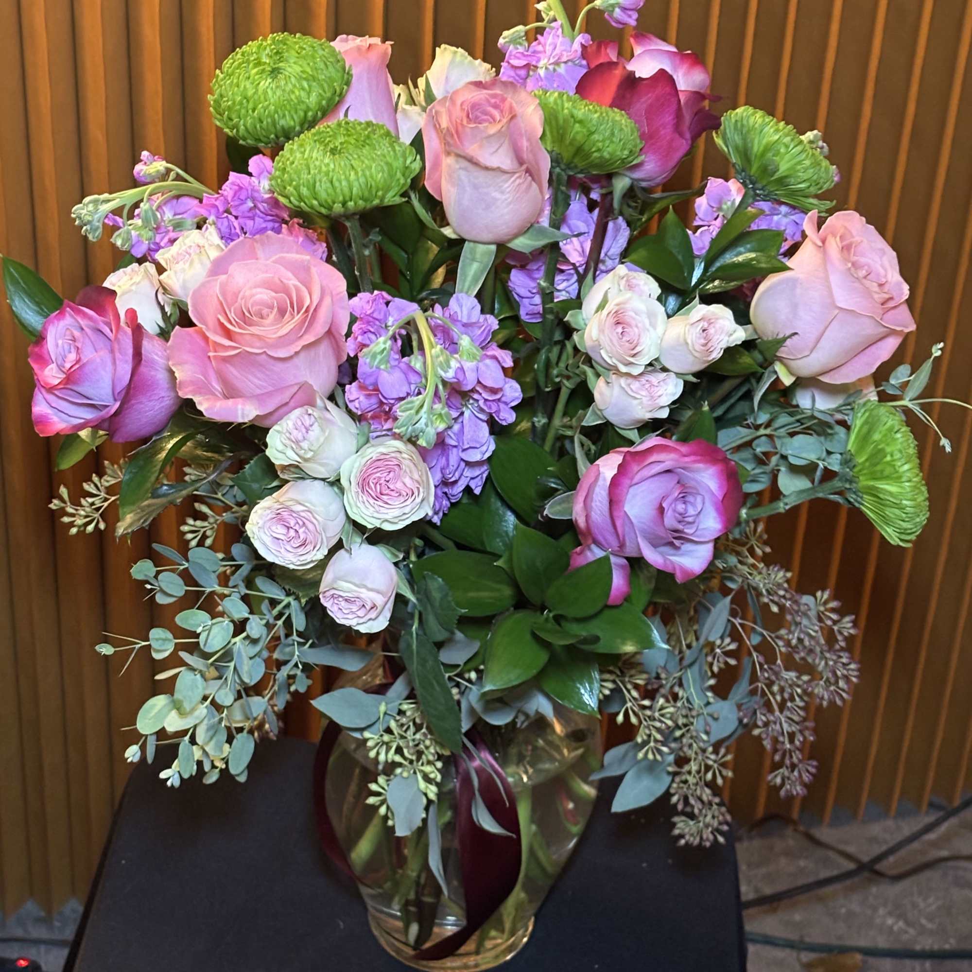 Pink and lavender roses in a glass vase with green button mums