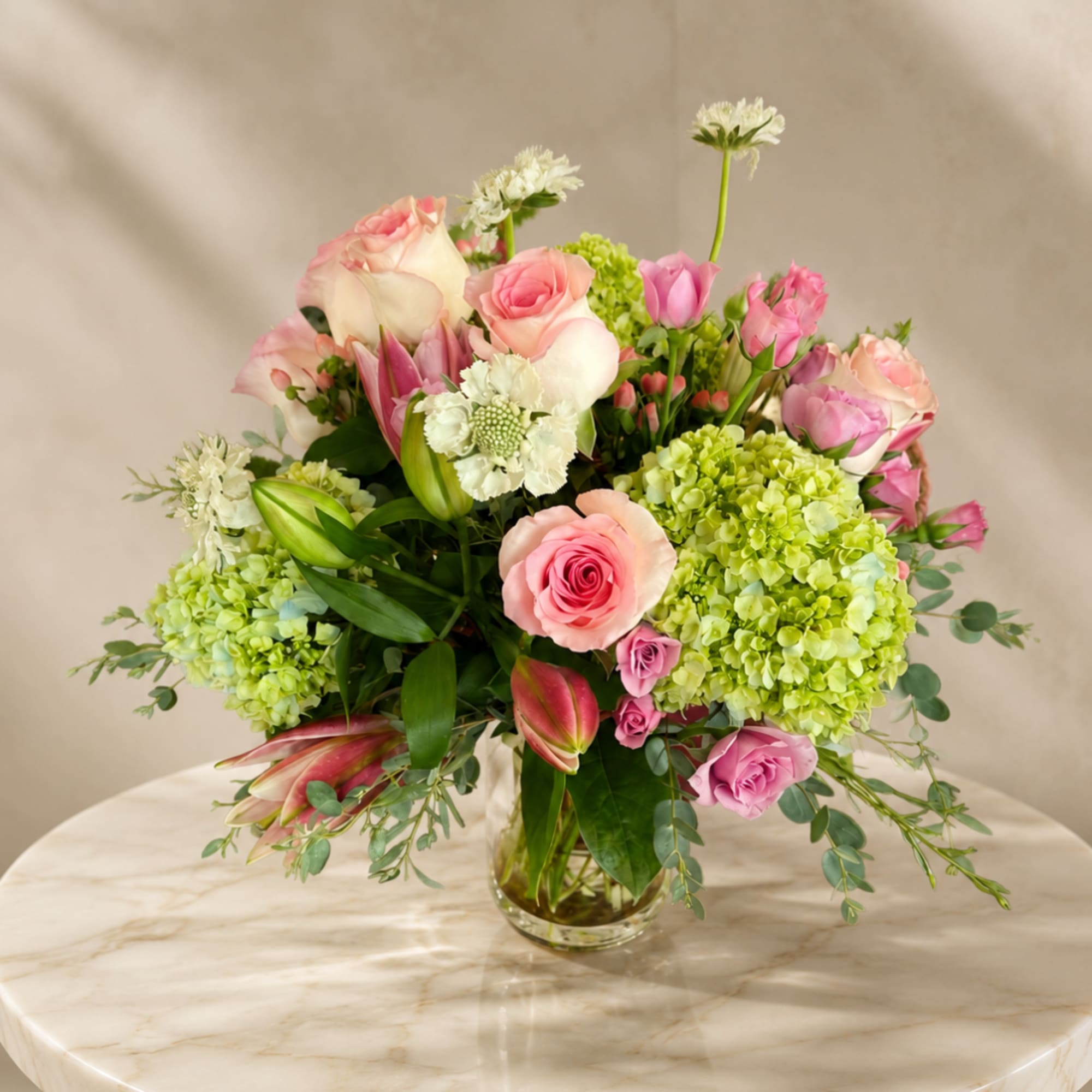 Pink roses and green hydrangeas in a clear glass vase
