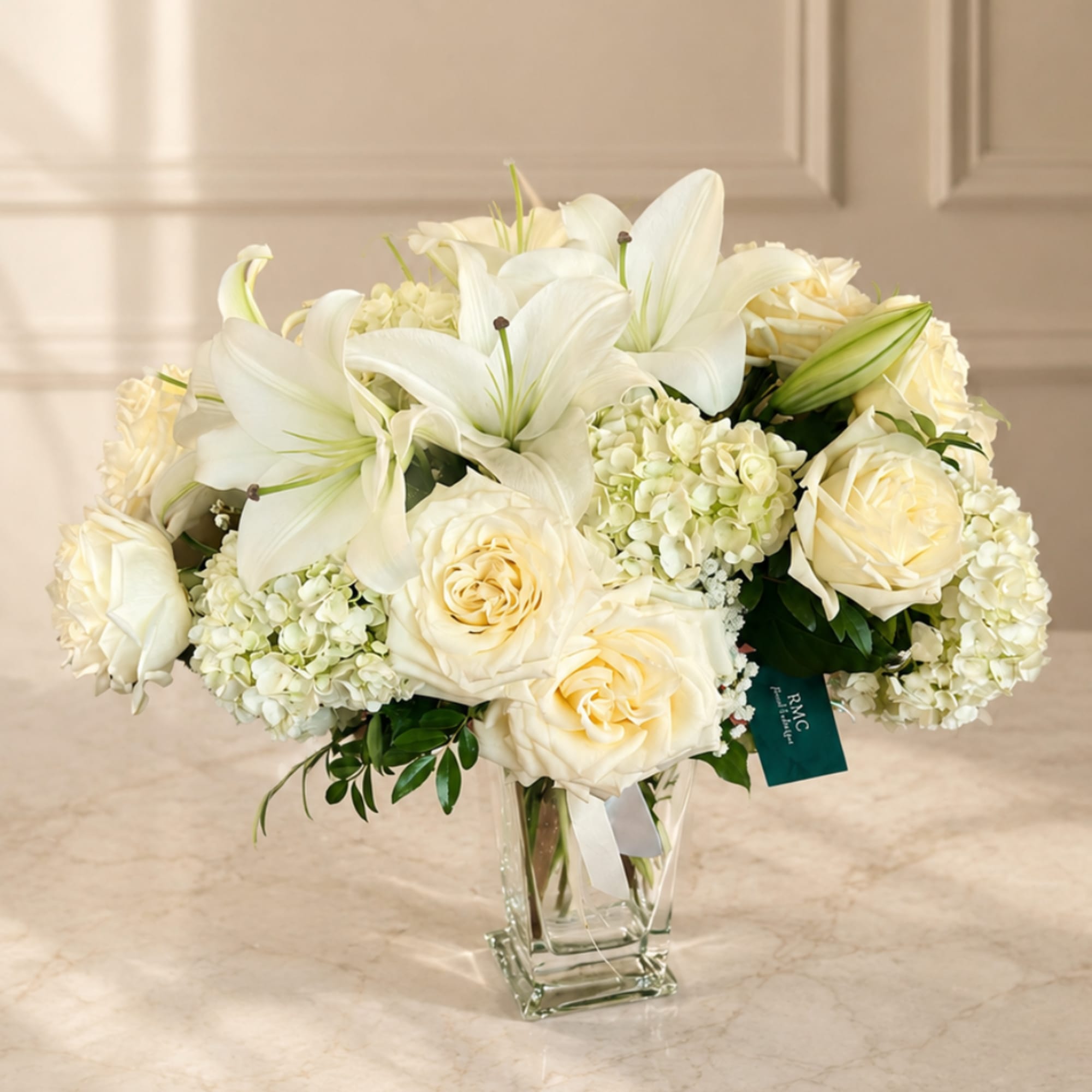 White lilies and cream roses in a clear glass vase