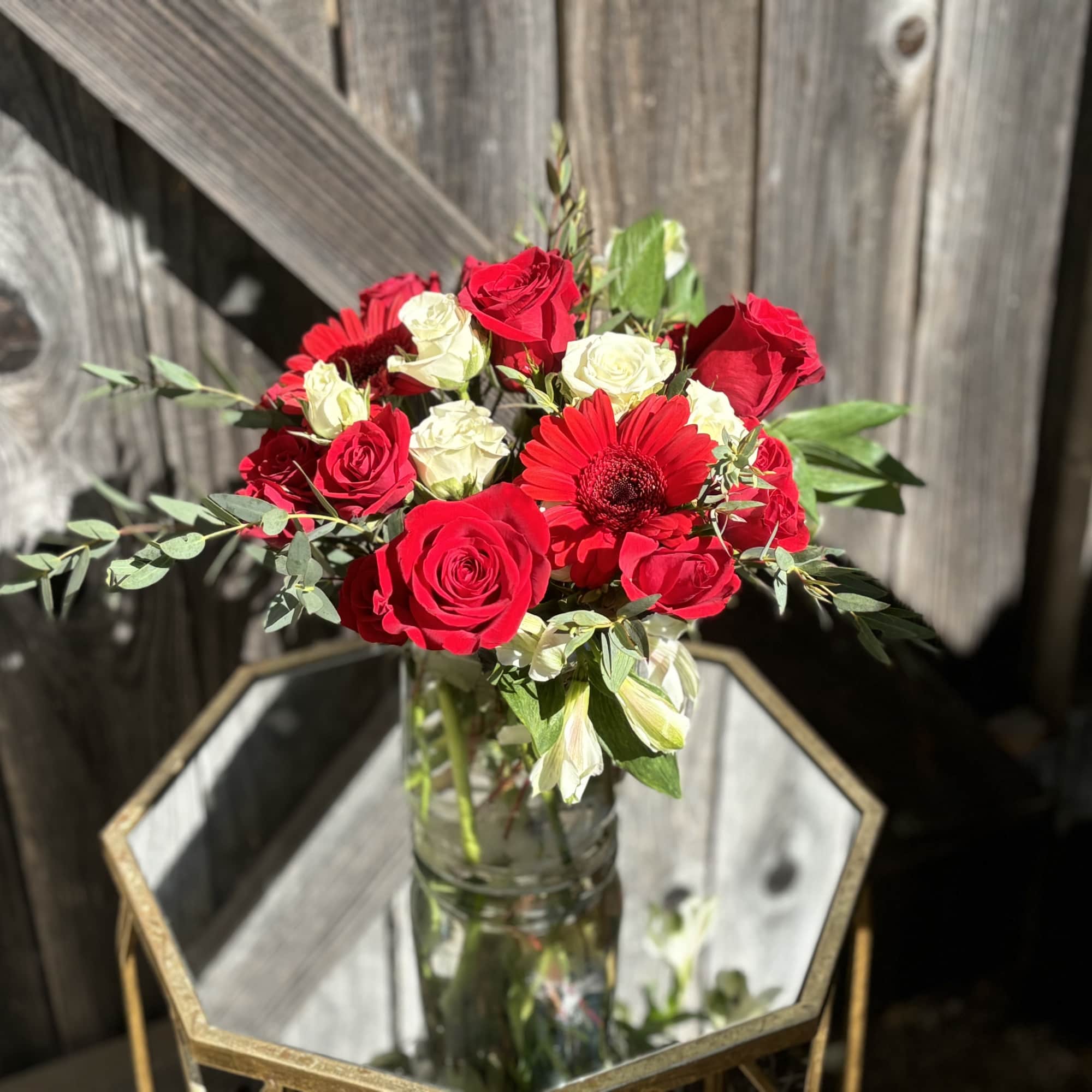 Red and white roses with a red gerbera daisy in a glass vase, photo 2 of 2