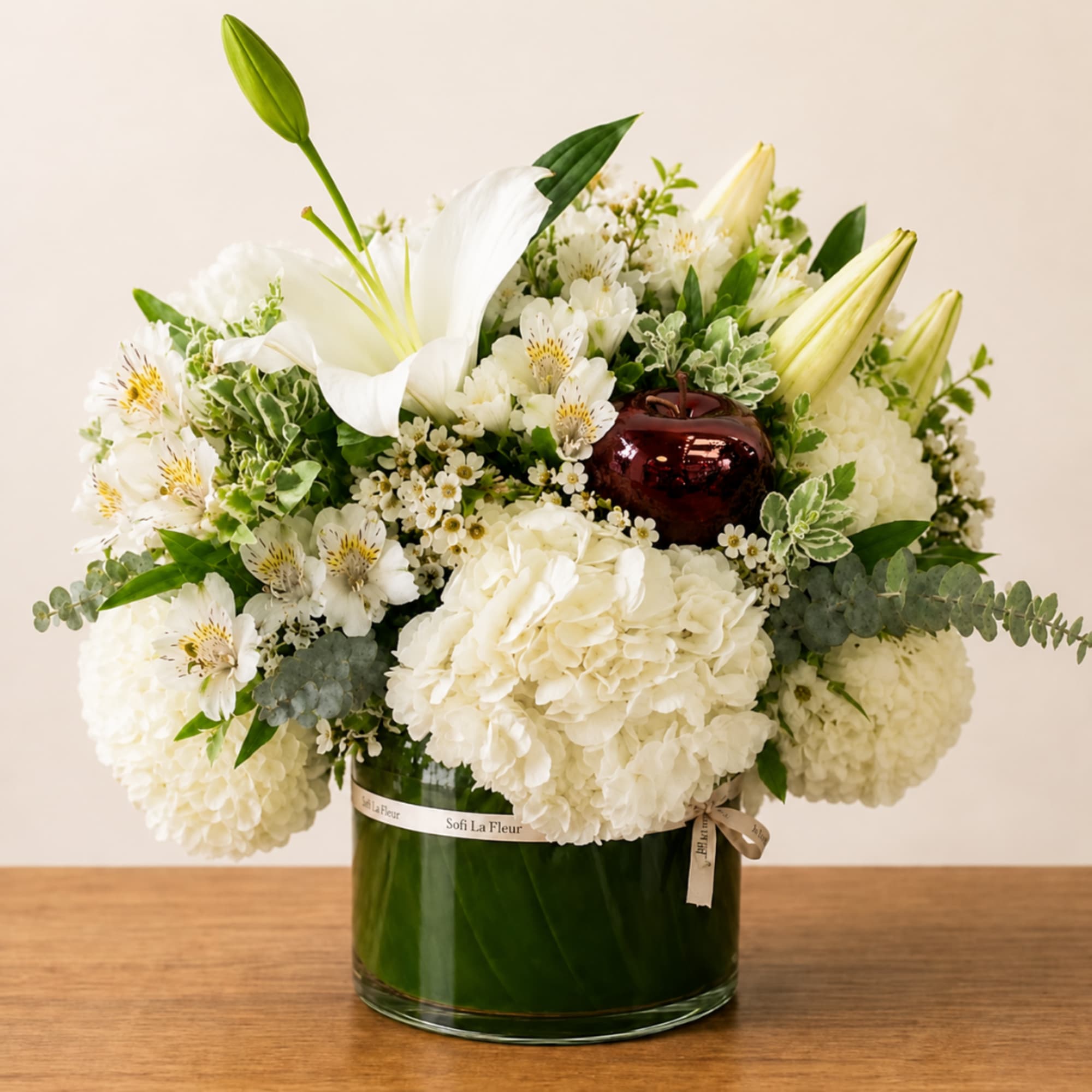 White floral arrangement in a glass vase with lilies and hydrangeas