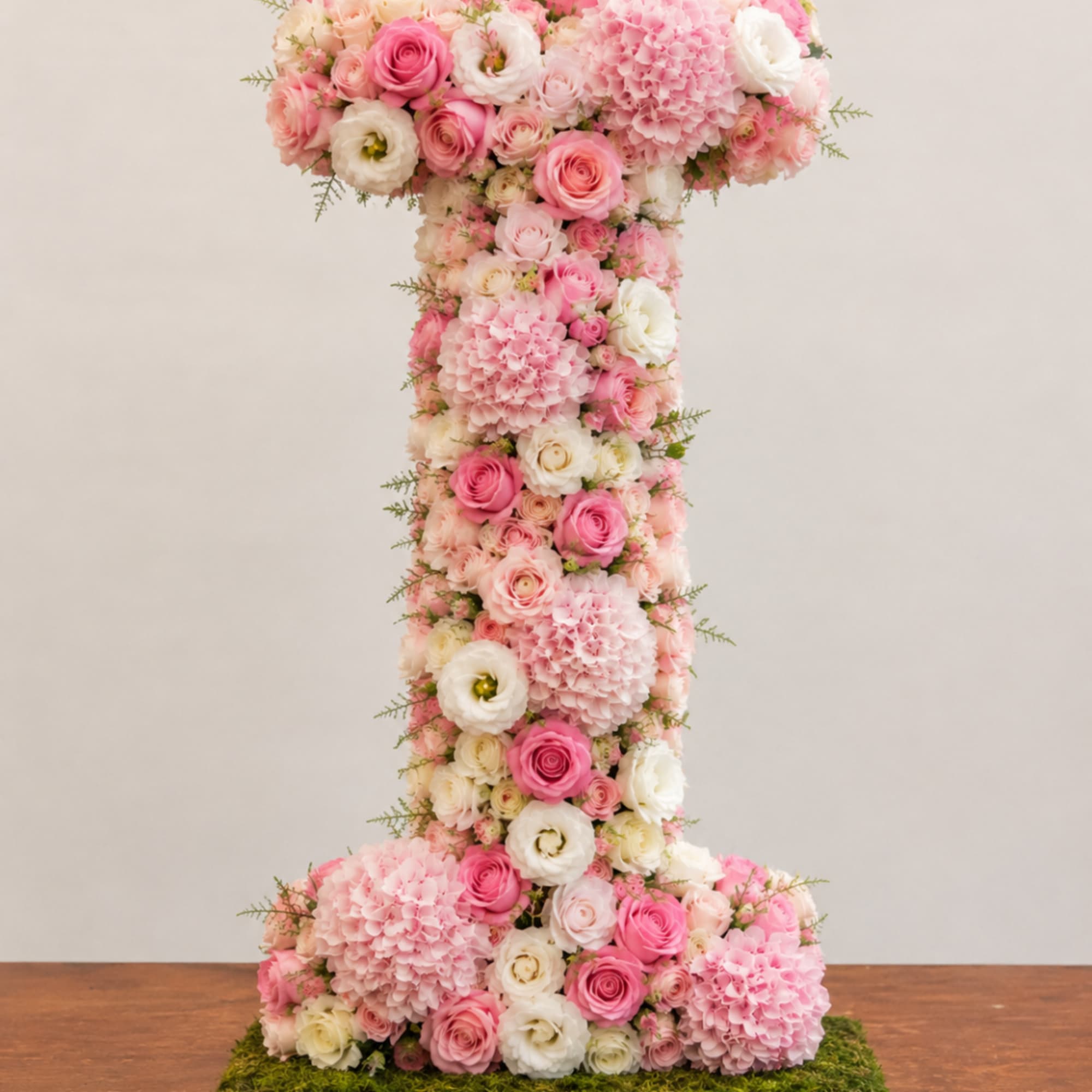 Tall pink and white floral arrangement shaped like a number one