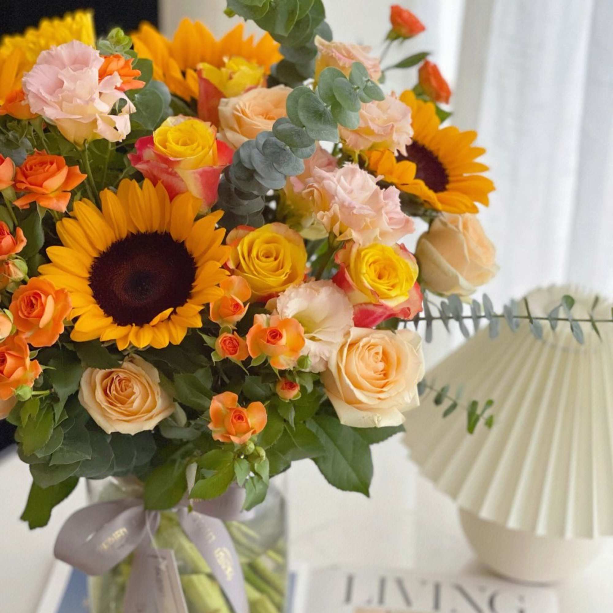 Bouquet of sunflowers, roses, and carnations in a glass vase