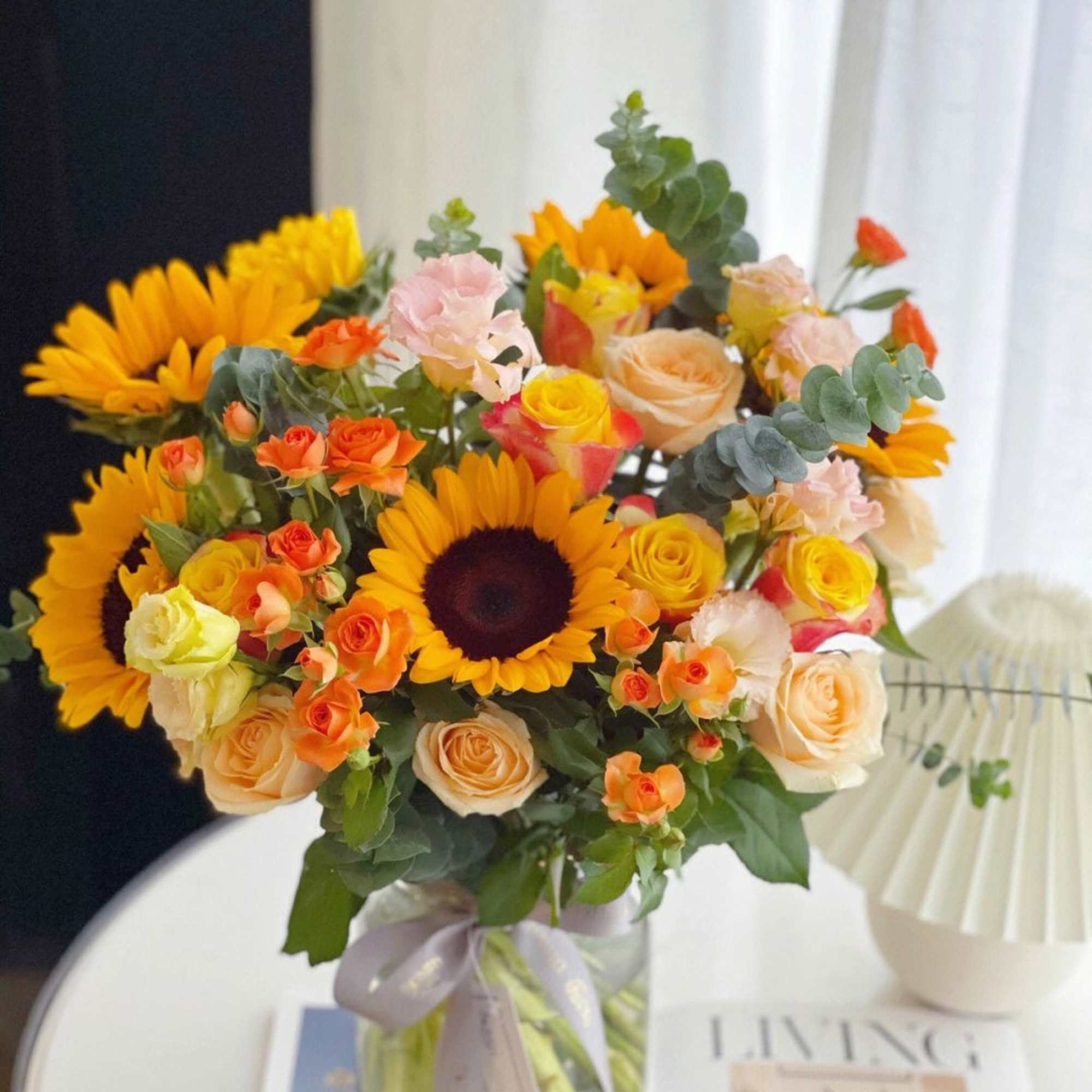 Bouquet of sunflowers and peach roses in a glass vase
