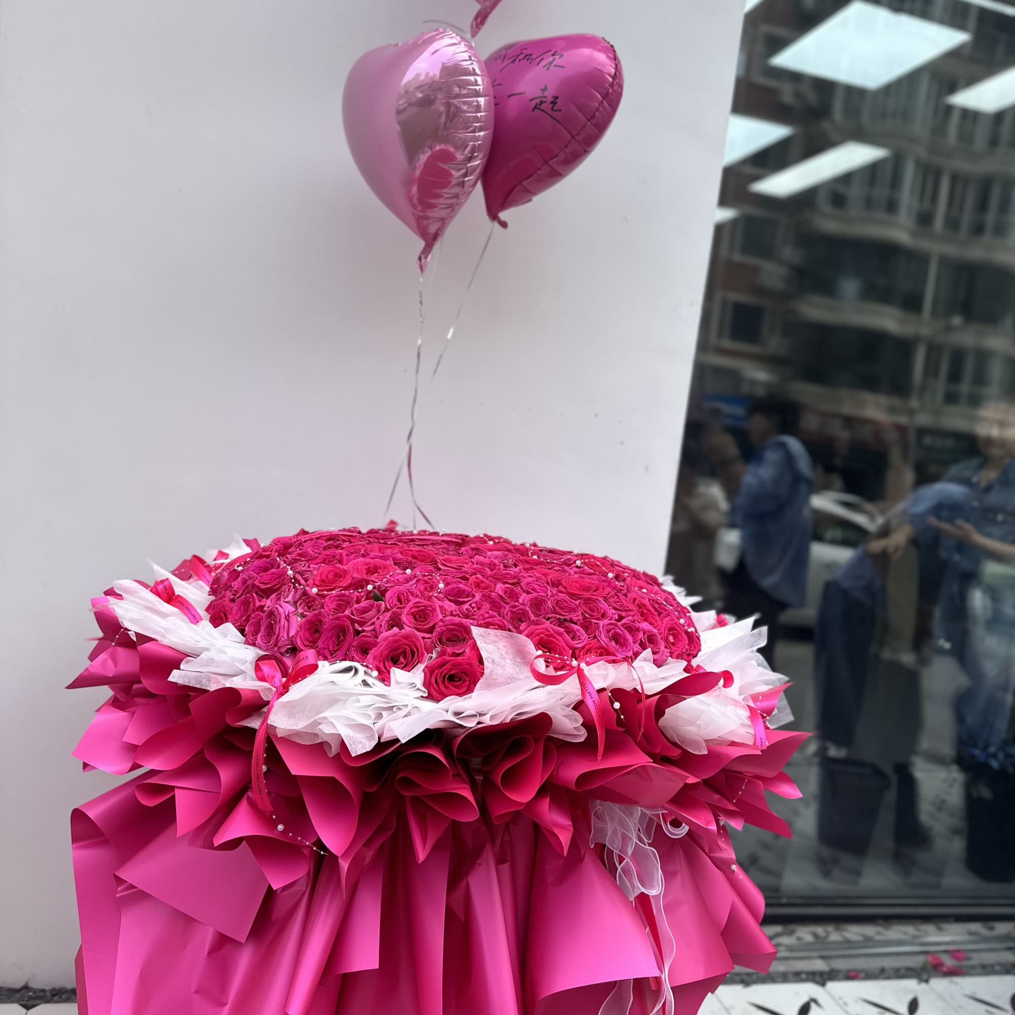 Large pink rose arrangement with heart balloons and layered pink wrapping