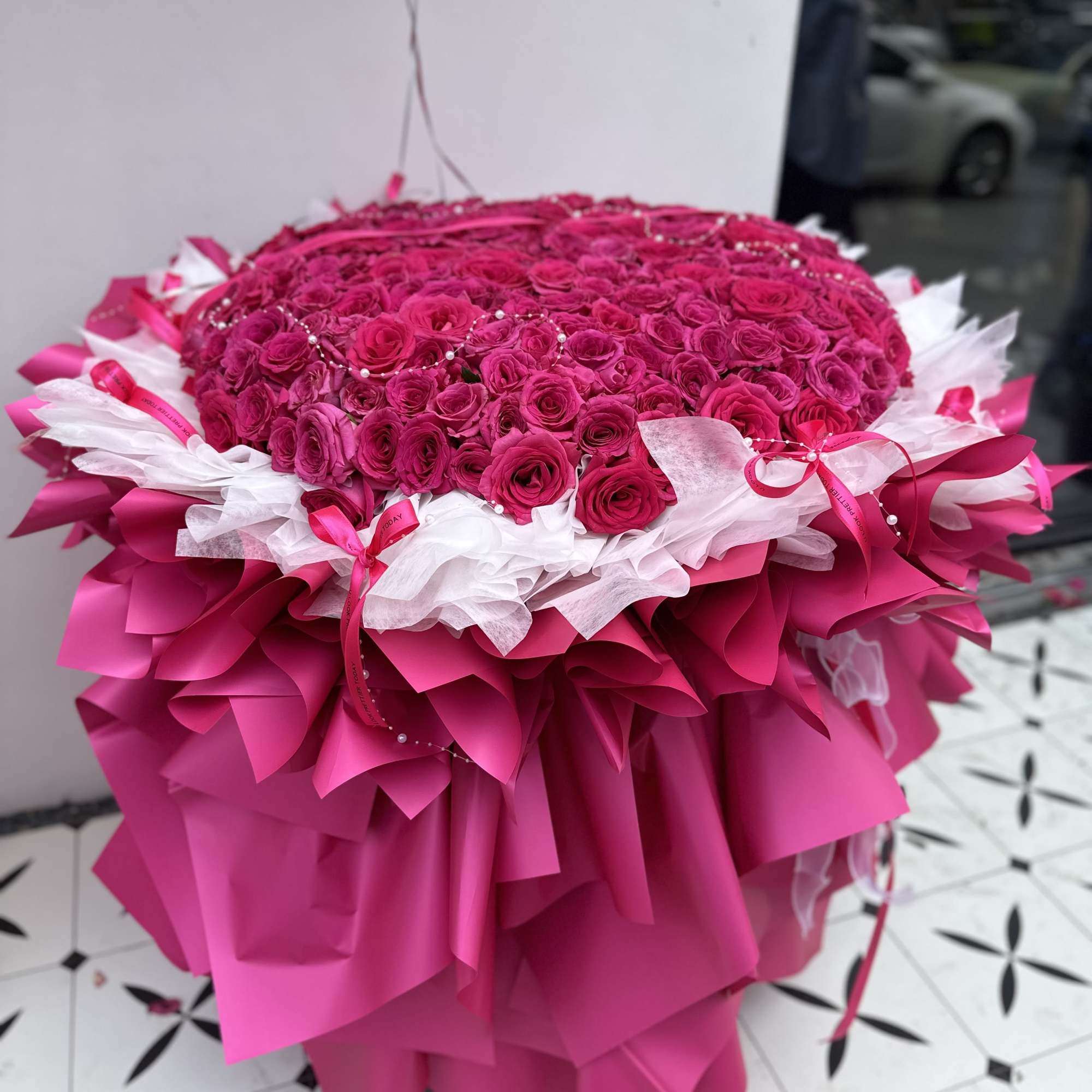 Large round bouquet of hot pink roses wrapped in pink and white paper