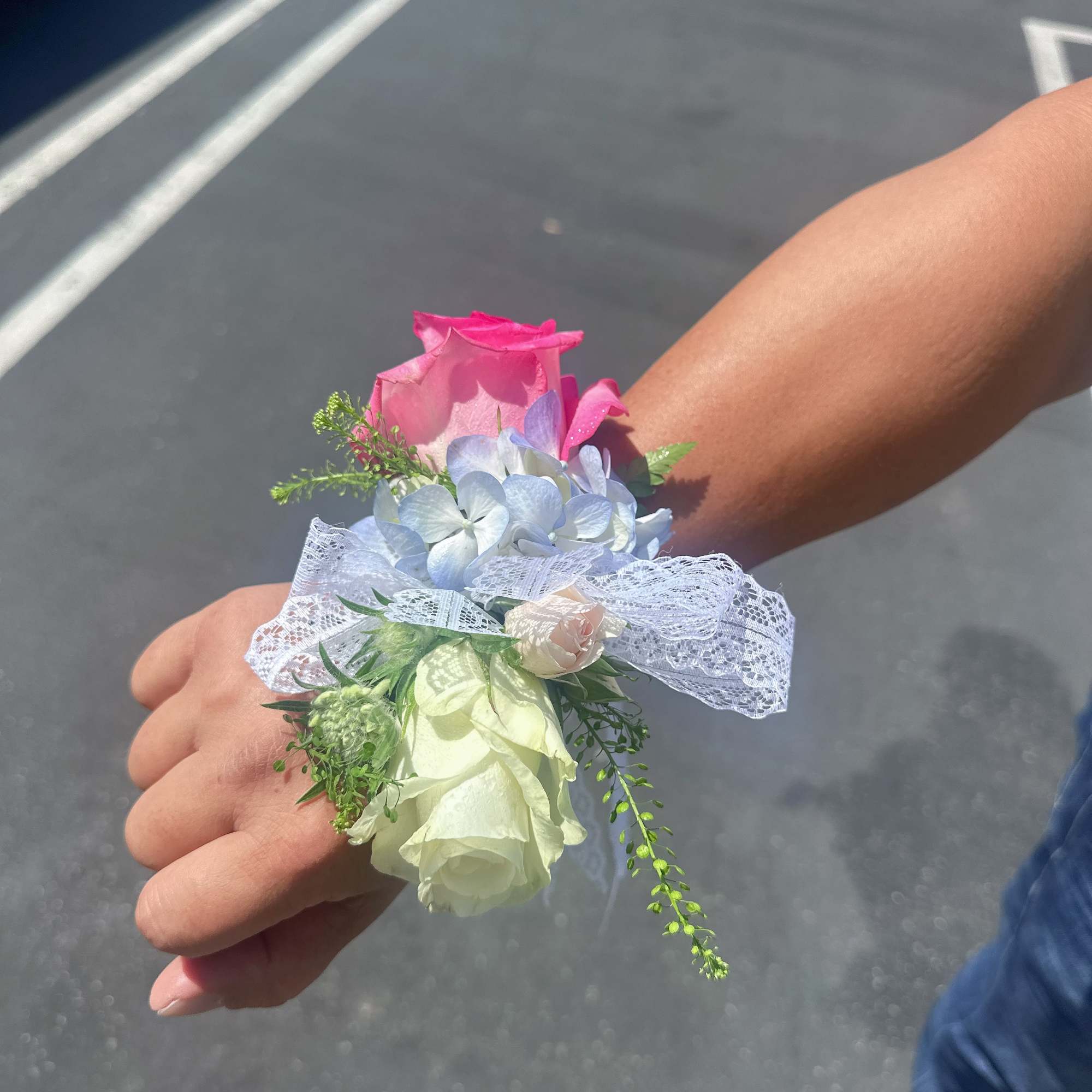 Small wrist corsage with pink and white roses and pale blue flowers