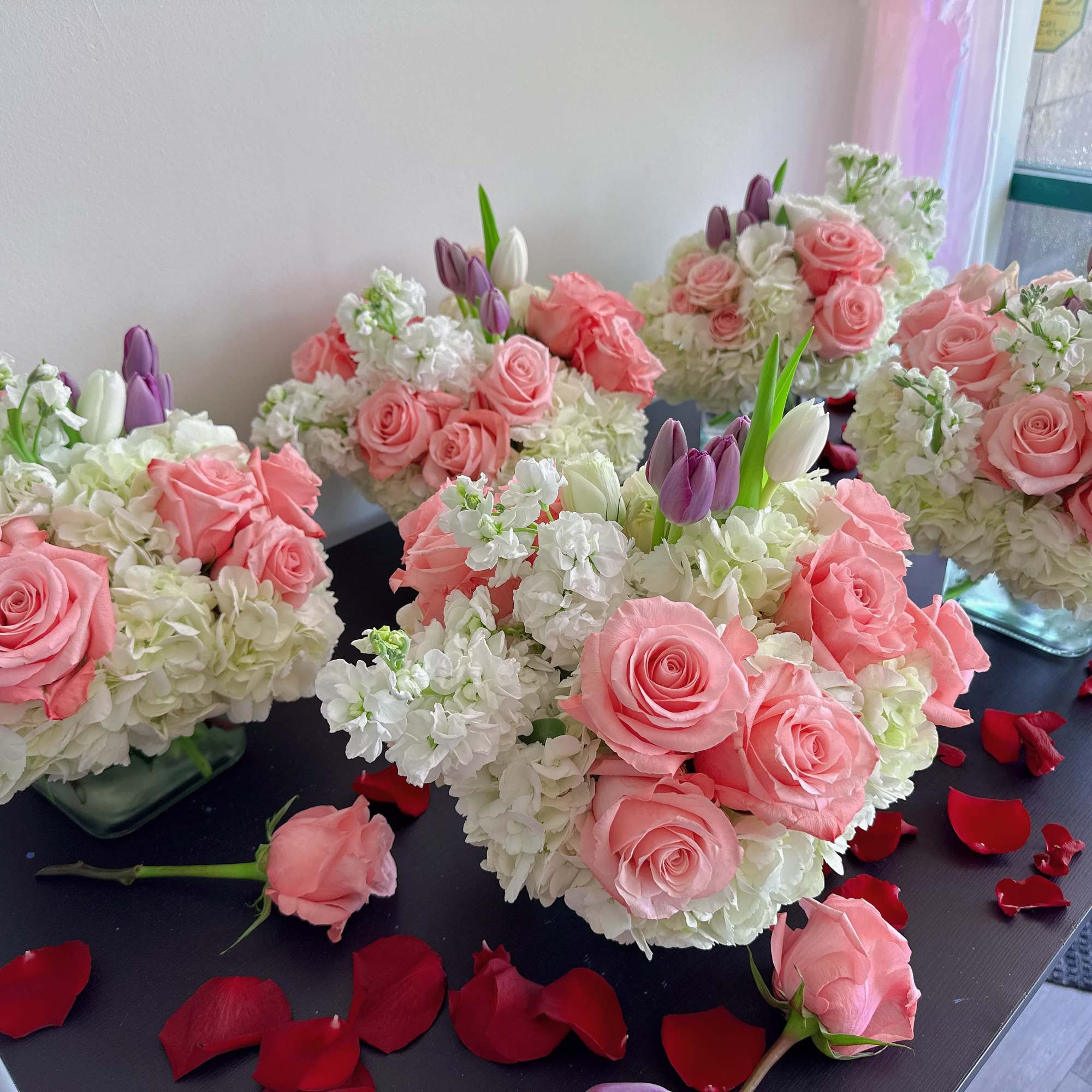 Pink rose and white hydrangea arrangements with tulips in square glass vases