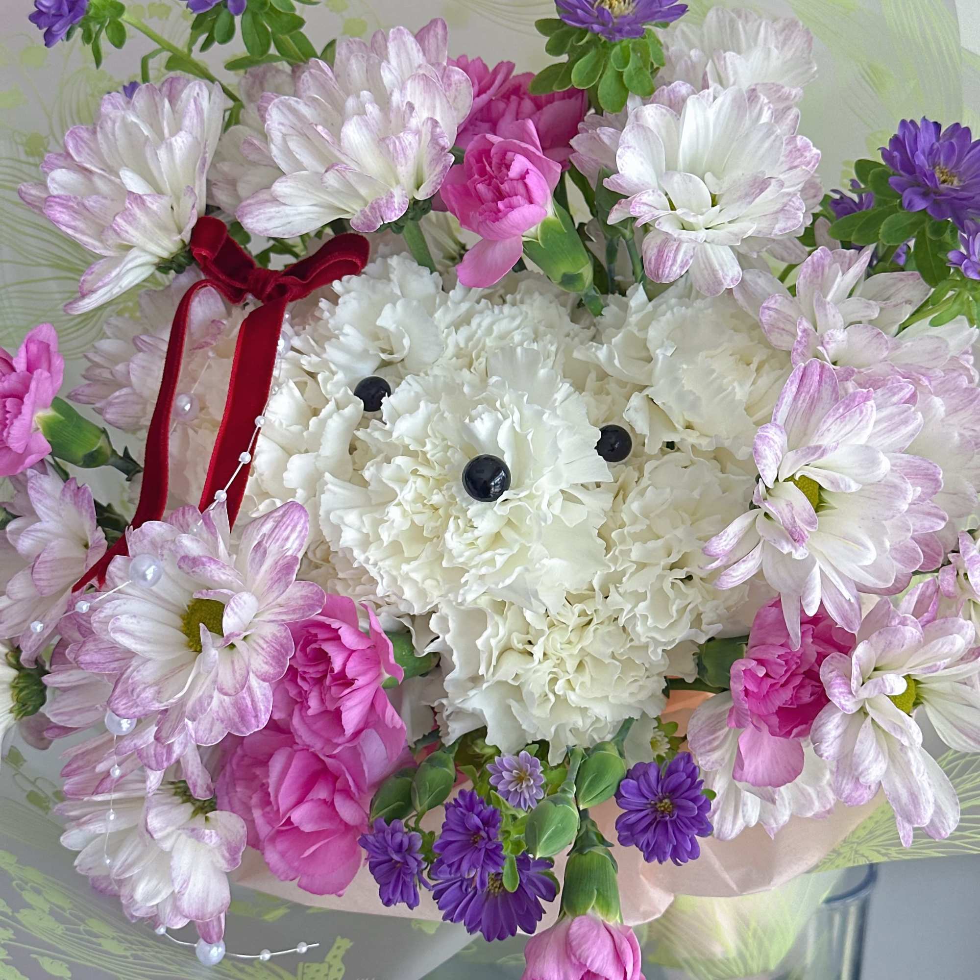 Bouquet of white and pink flowers with purple daisies in wrapping paper