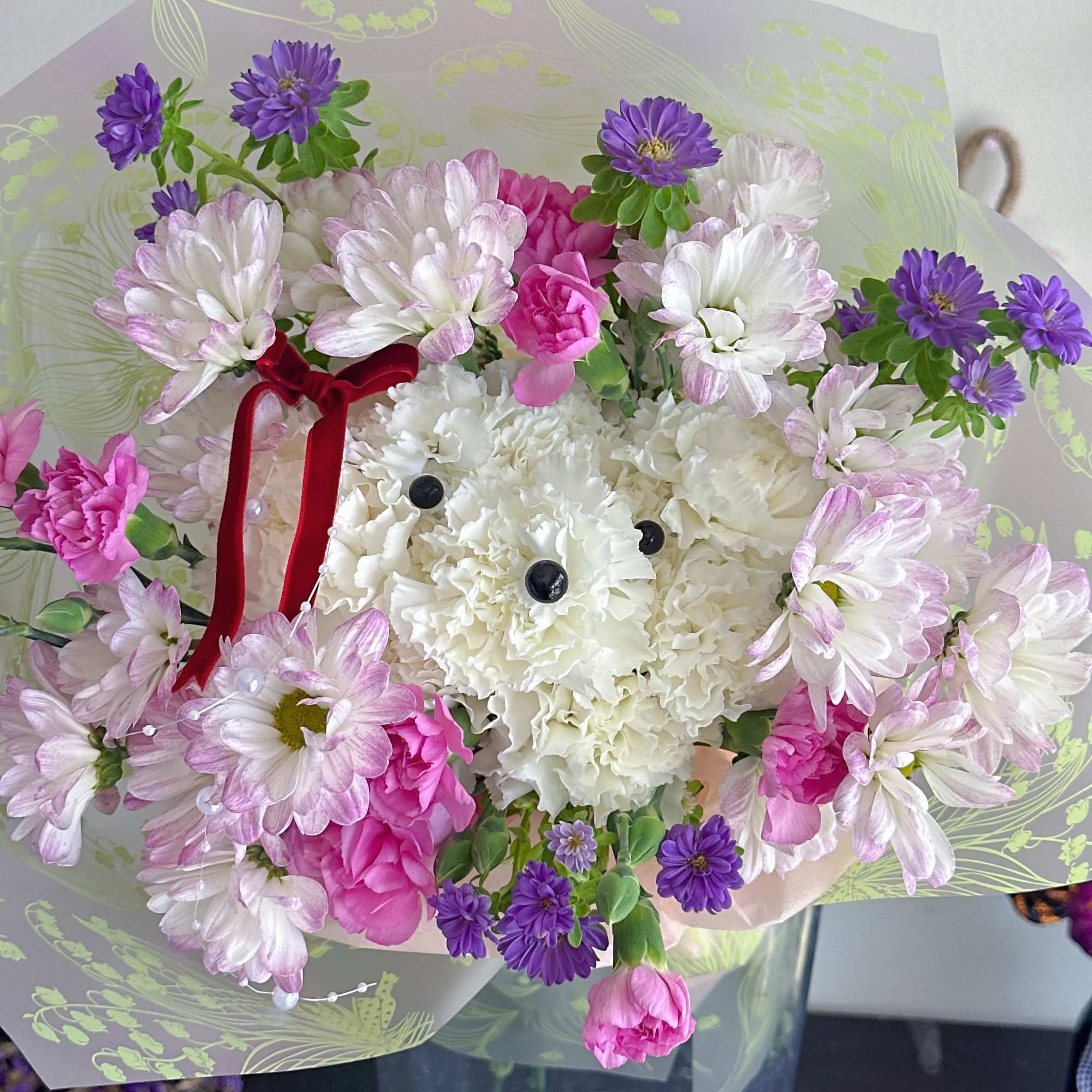 Bouquet of pink, white, and purple flowers wrapped in patterned paper