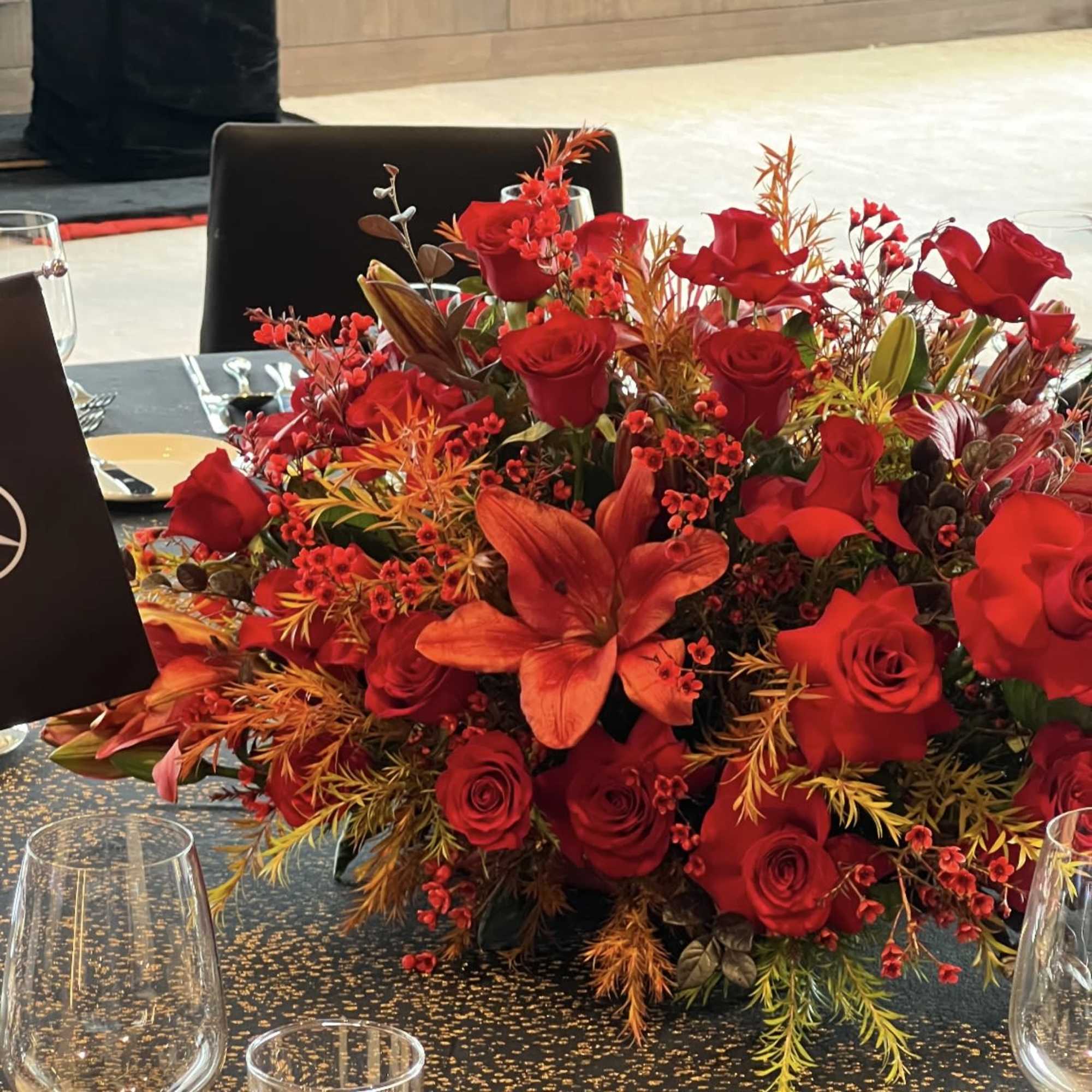 Red roses and orange lilies arranged in a low table centerpiece.