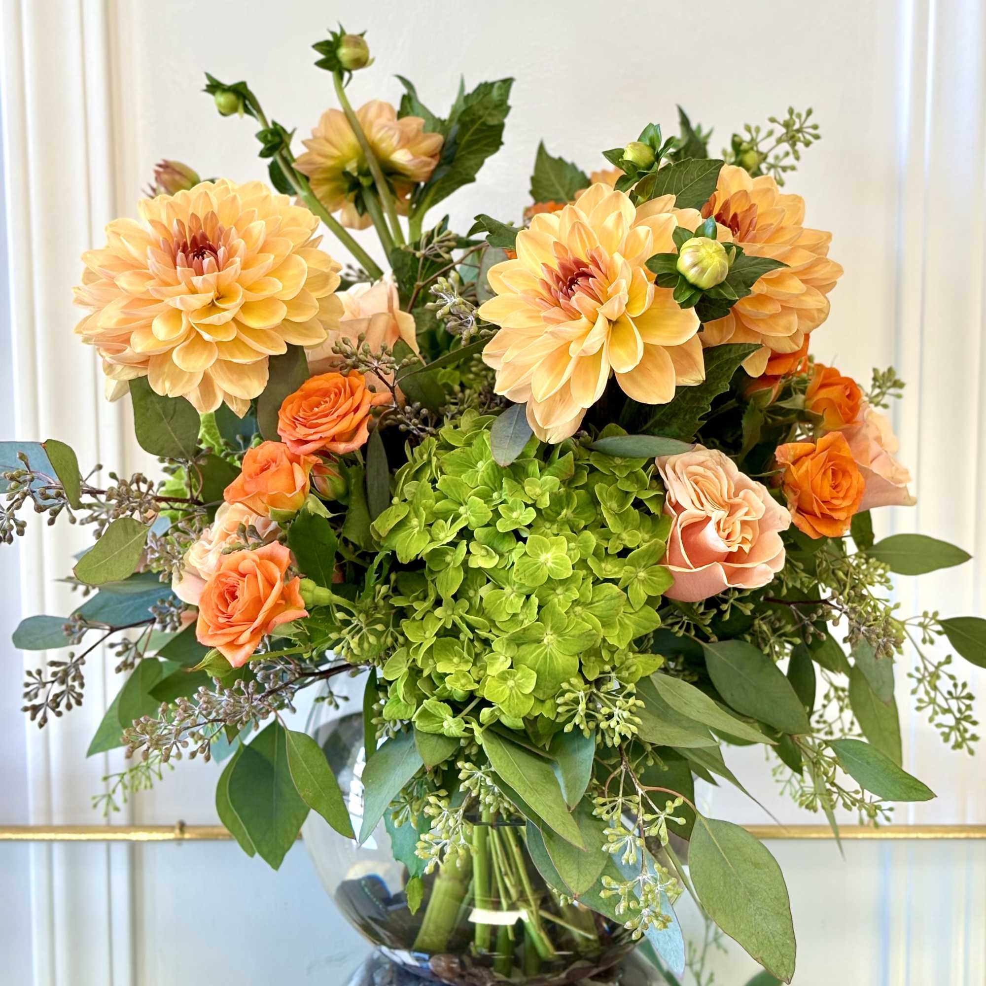 Bouquet of peach dahlias and orange roses in a glass vase