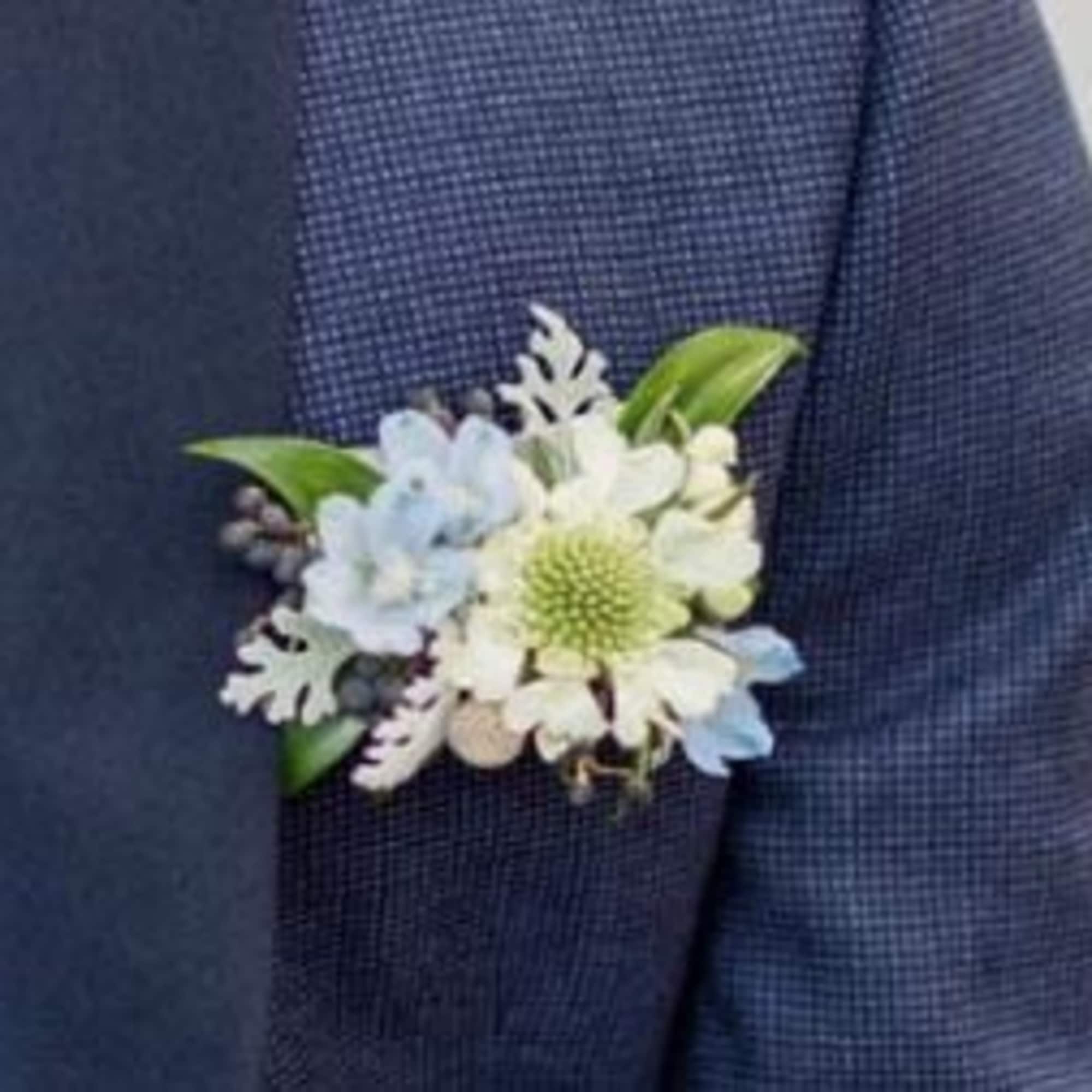 Small blue and white boutonniere pinned to a navy suit jacket