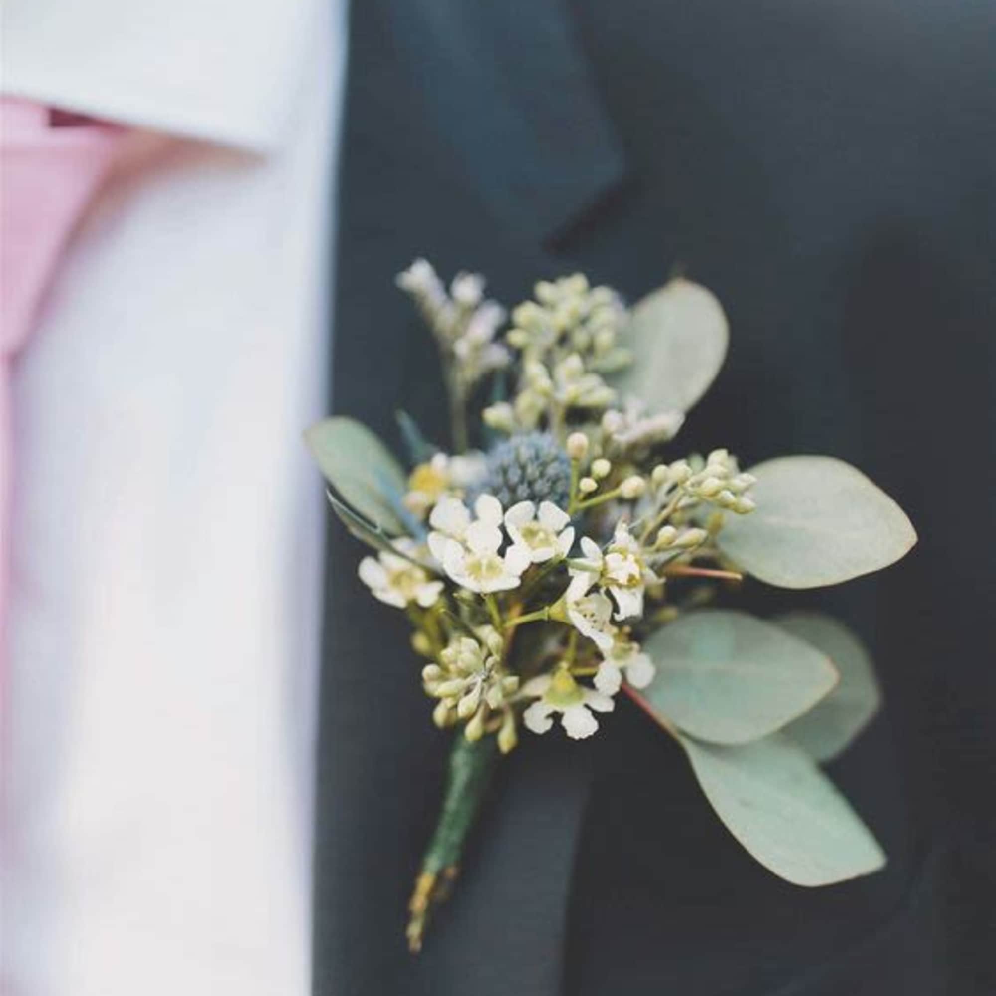 Small white and green boutonniere pinned to a dark suit lapel