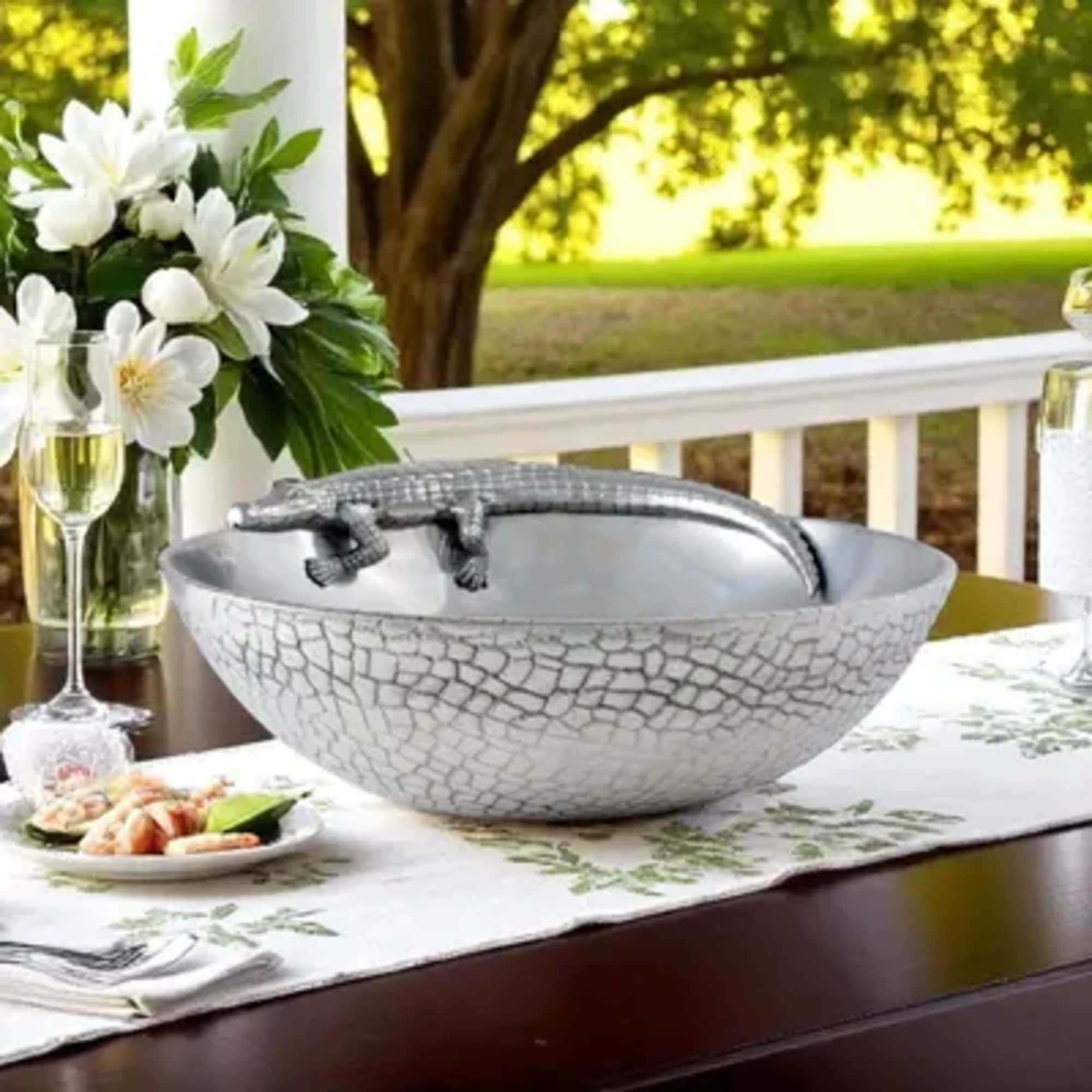 White floral arrangement beside a silver alligator-shaped bowl on a table