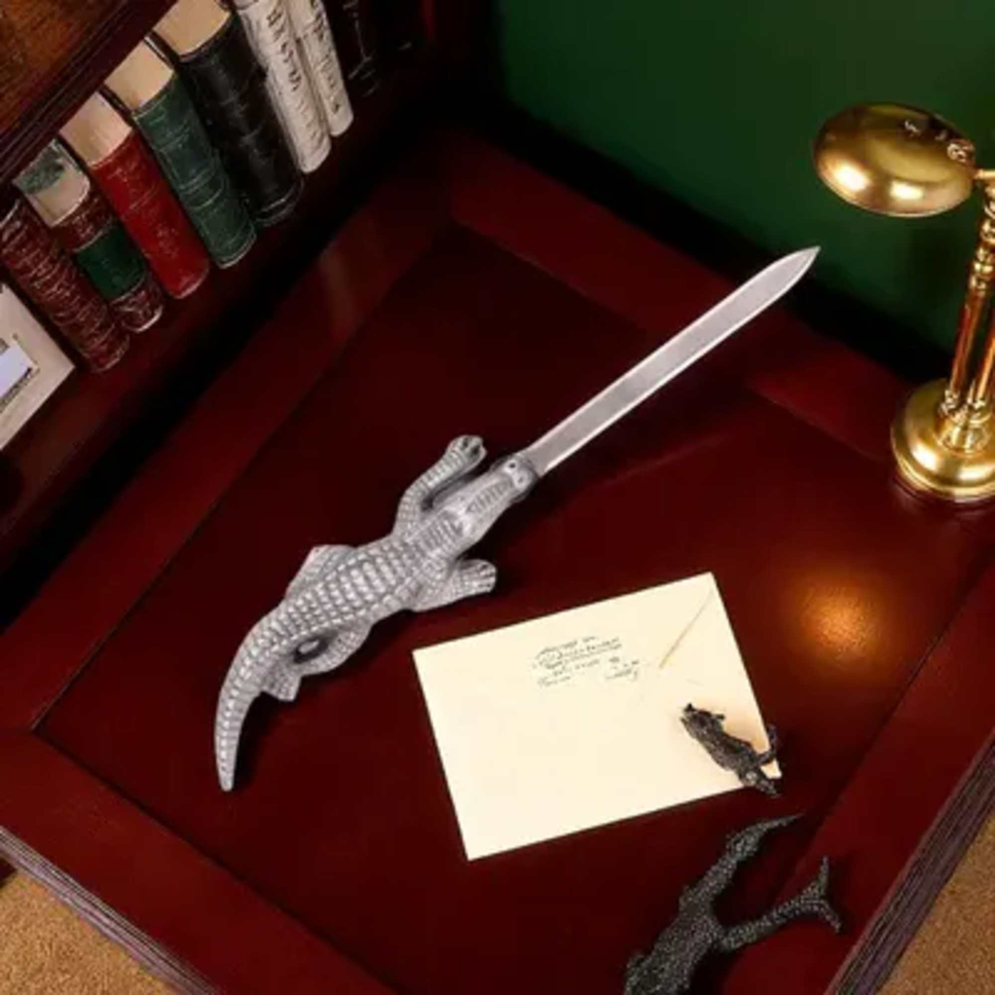 Decorative crocodile-shaped letter opener on a desk with a card