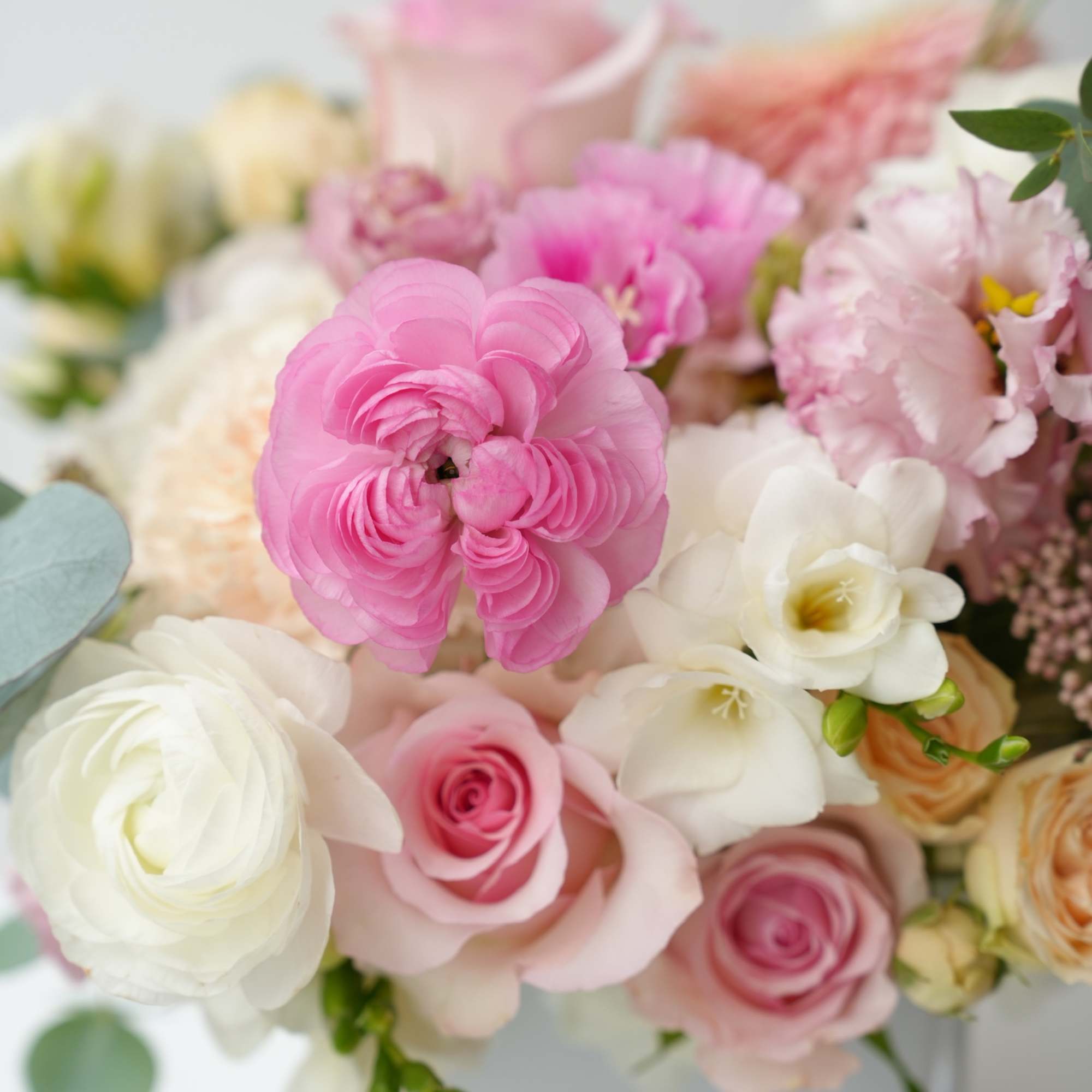 Pink and white mixed bouquet with roses and ranunculus in a white vase