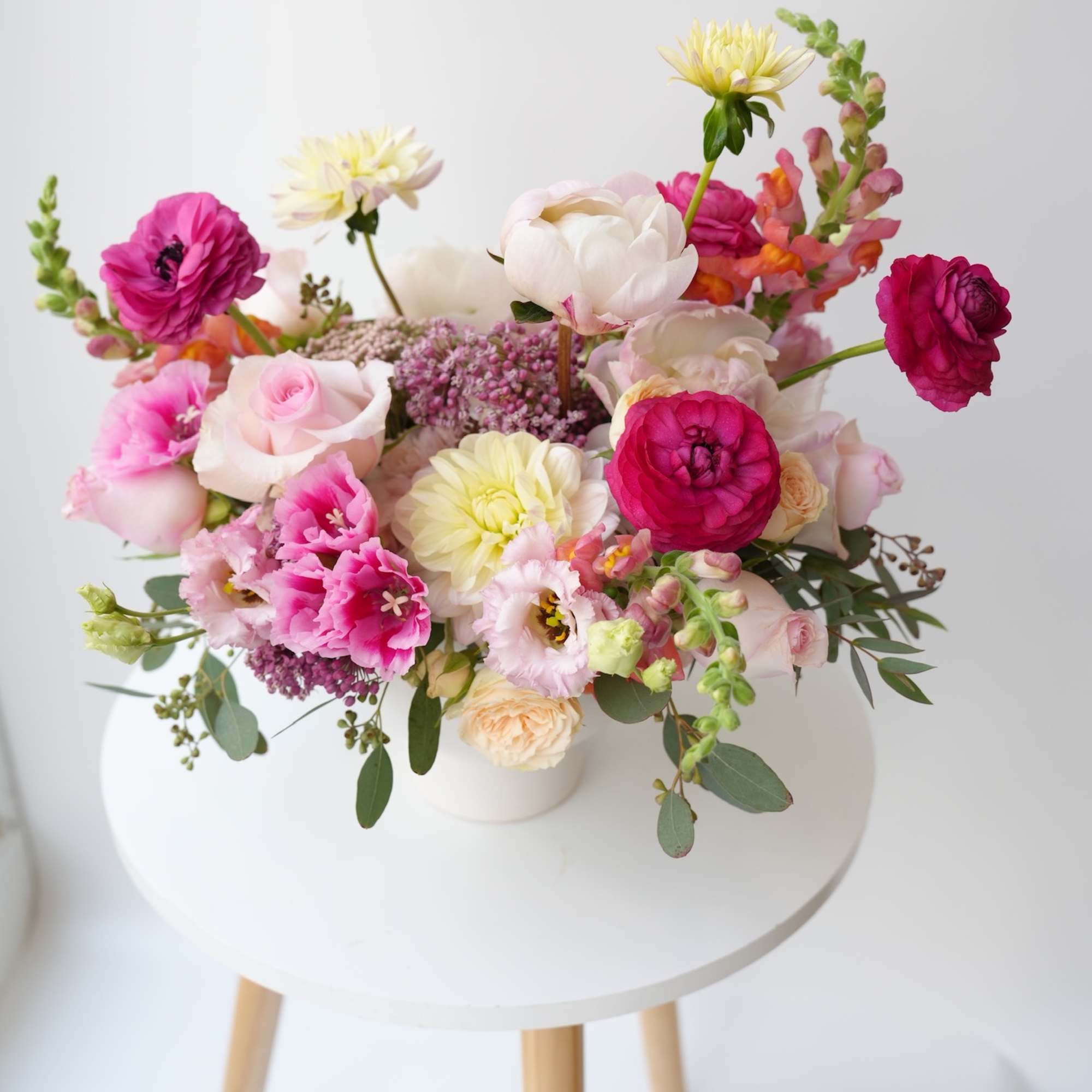 Mixed bouquet of pink, white, and yellow flowers in a white vase
