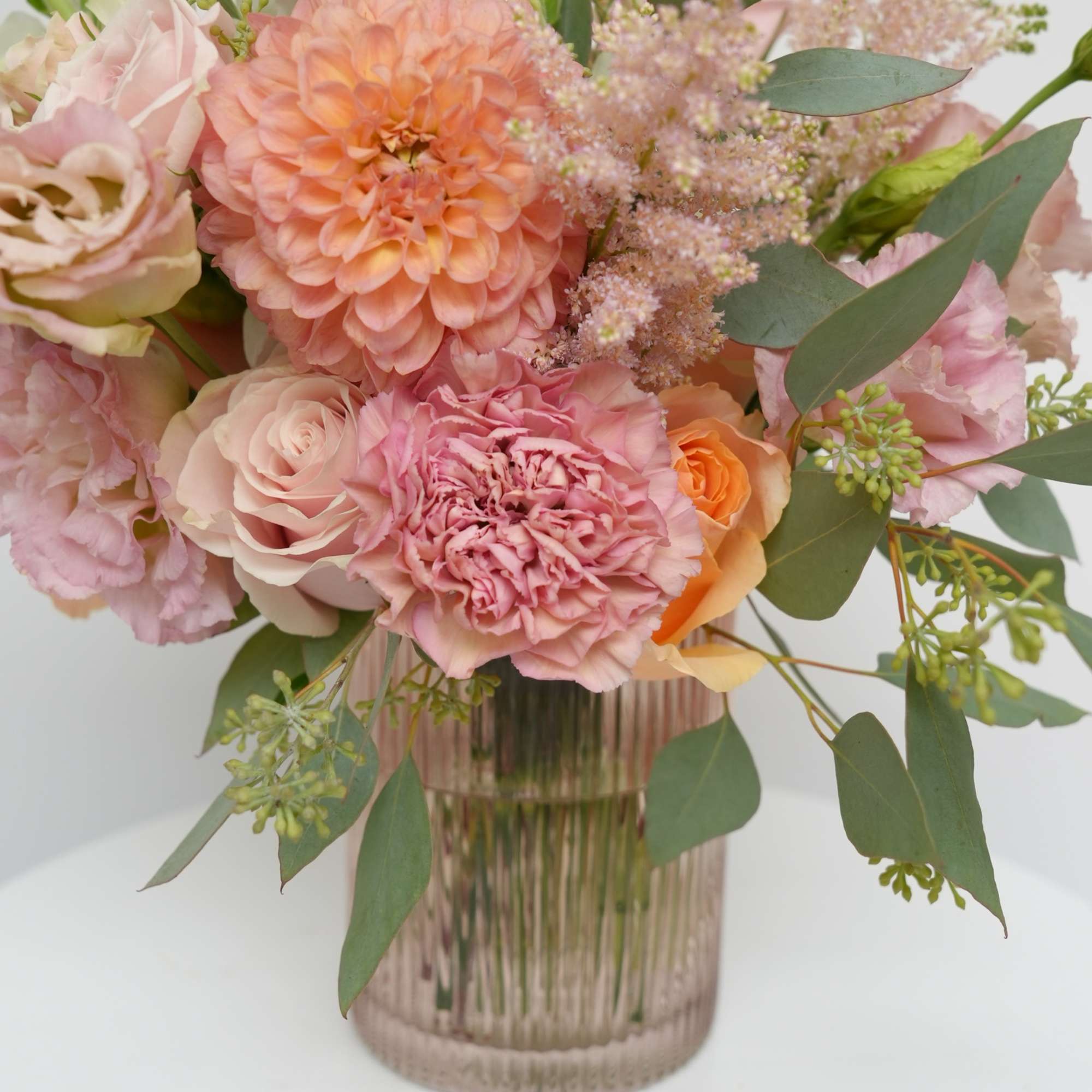 Pink and peach bouquet in a ribbed glass vase