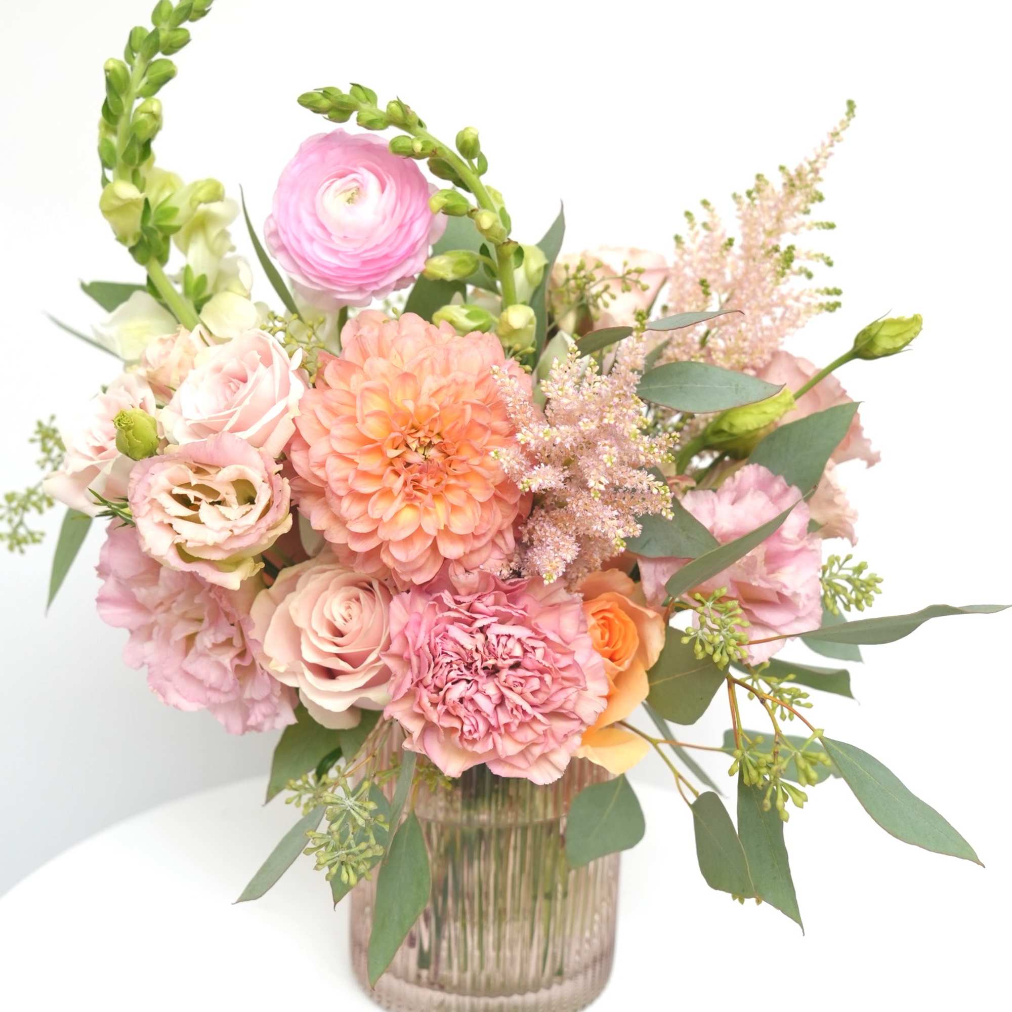 Pink and peach floral arrangement in a ribbed glass vase
