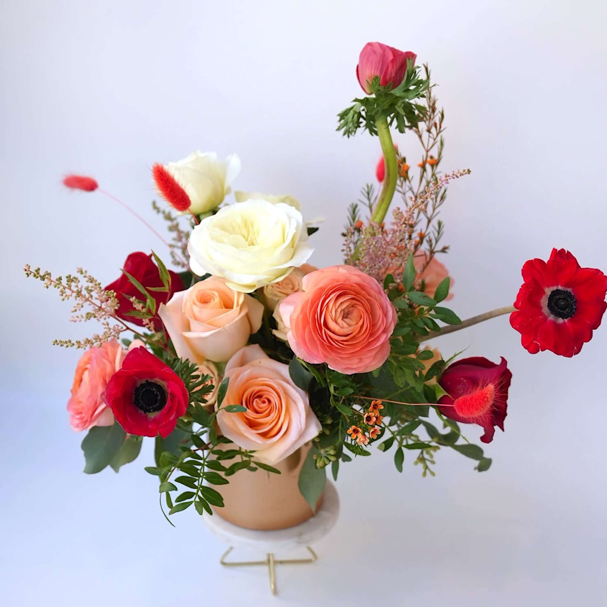 Mixed bouquet of roses and red anemones in a small vase