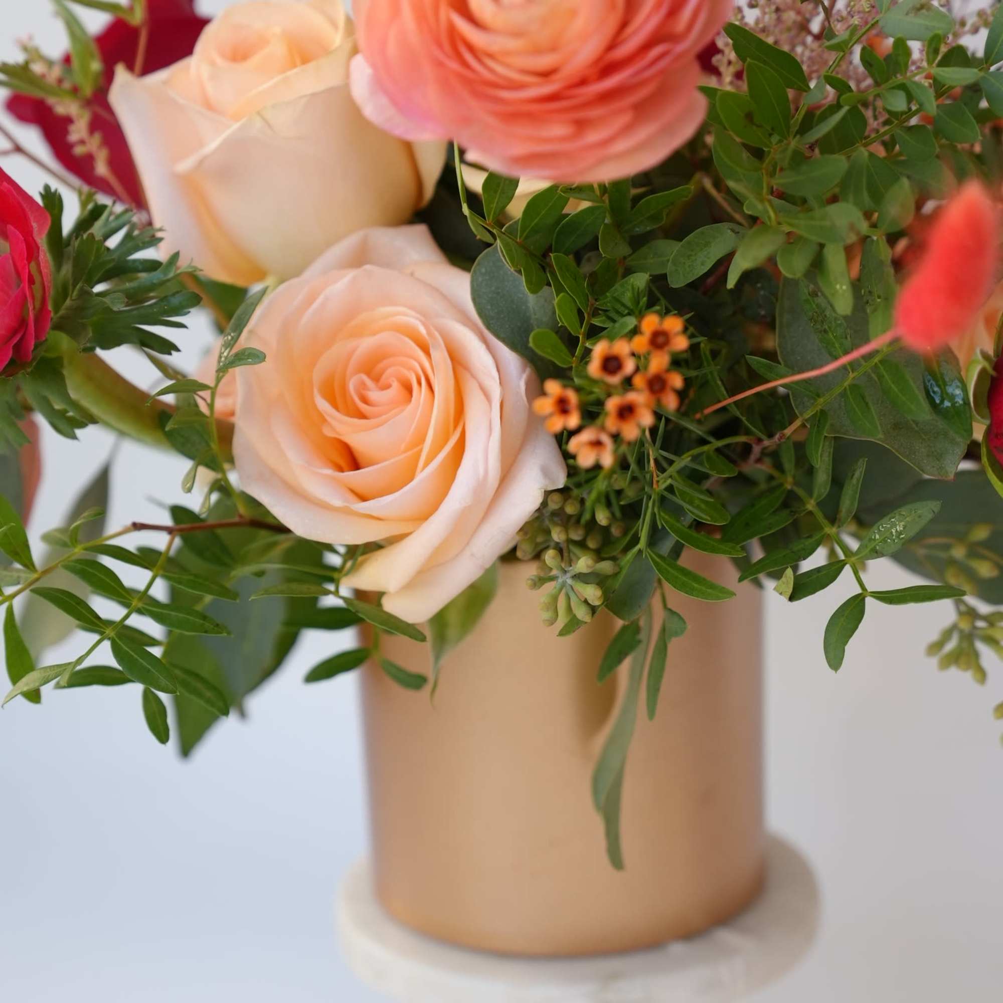 Peach and white roses arranged in a gold vase