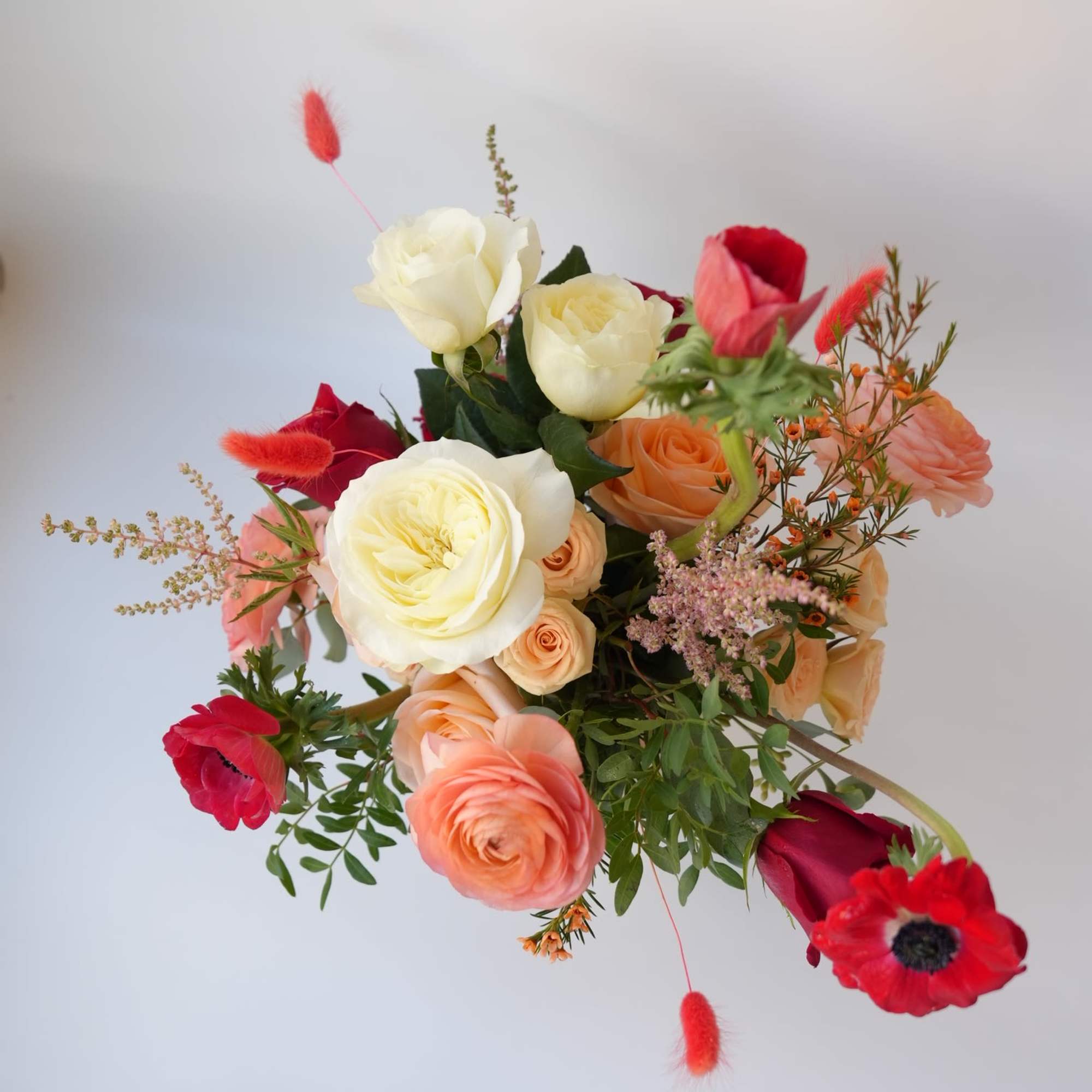 Mixed bouquet of cream, peach, and red flowers with airy accents