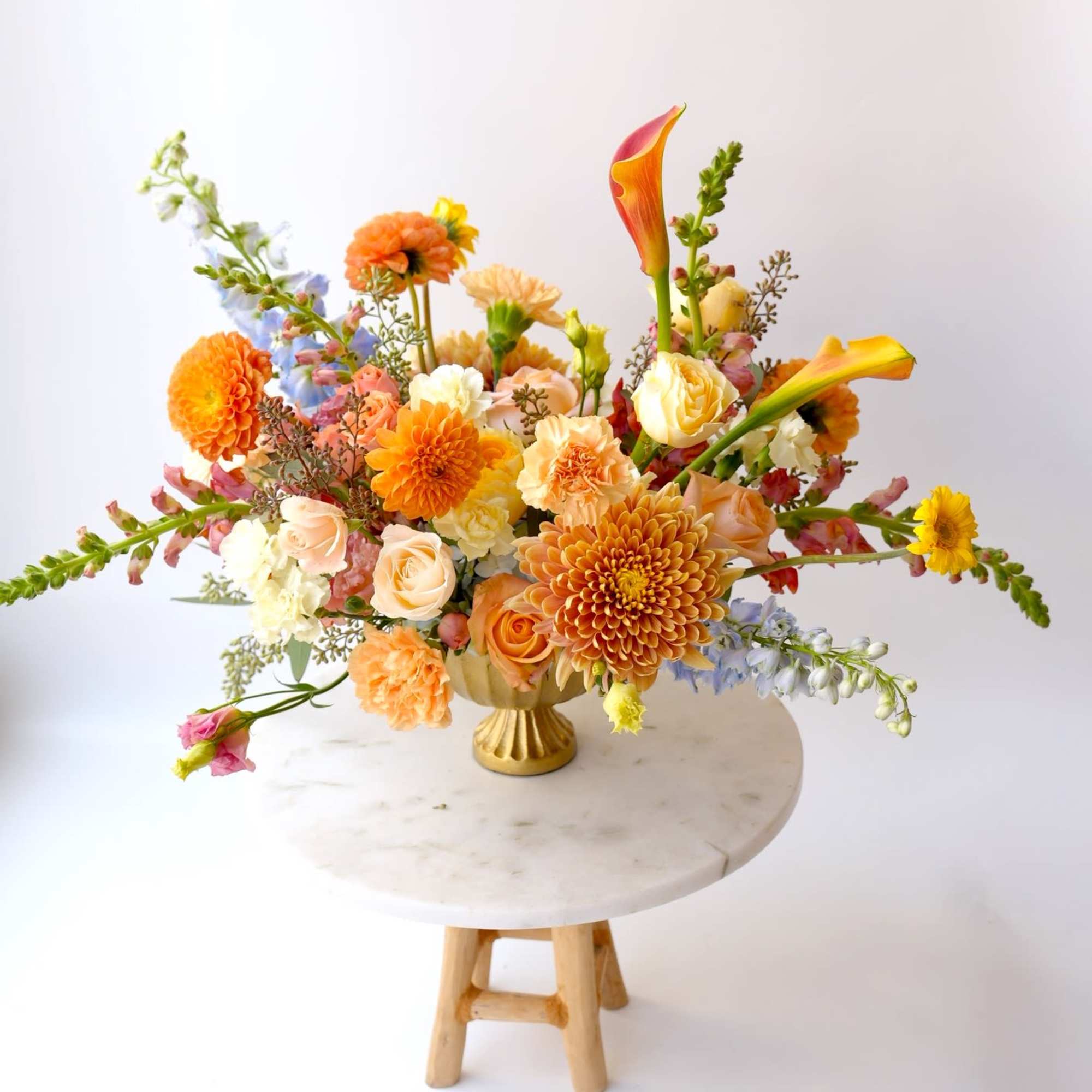 Colorful mixed flower arrangement in a gold vase on a round table