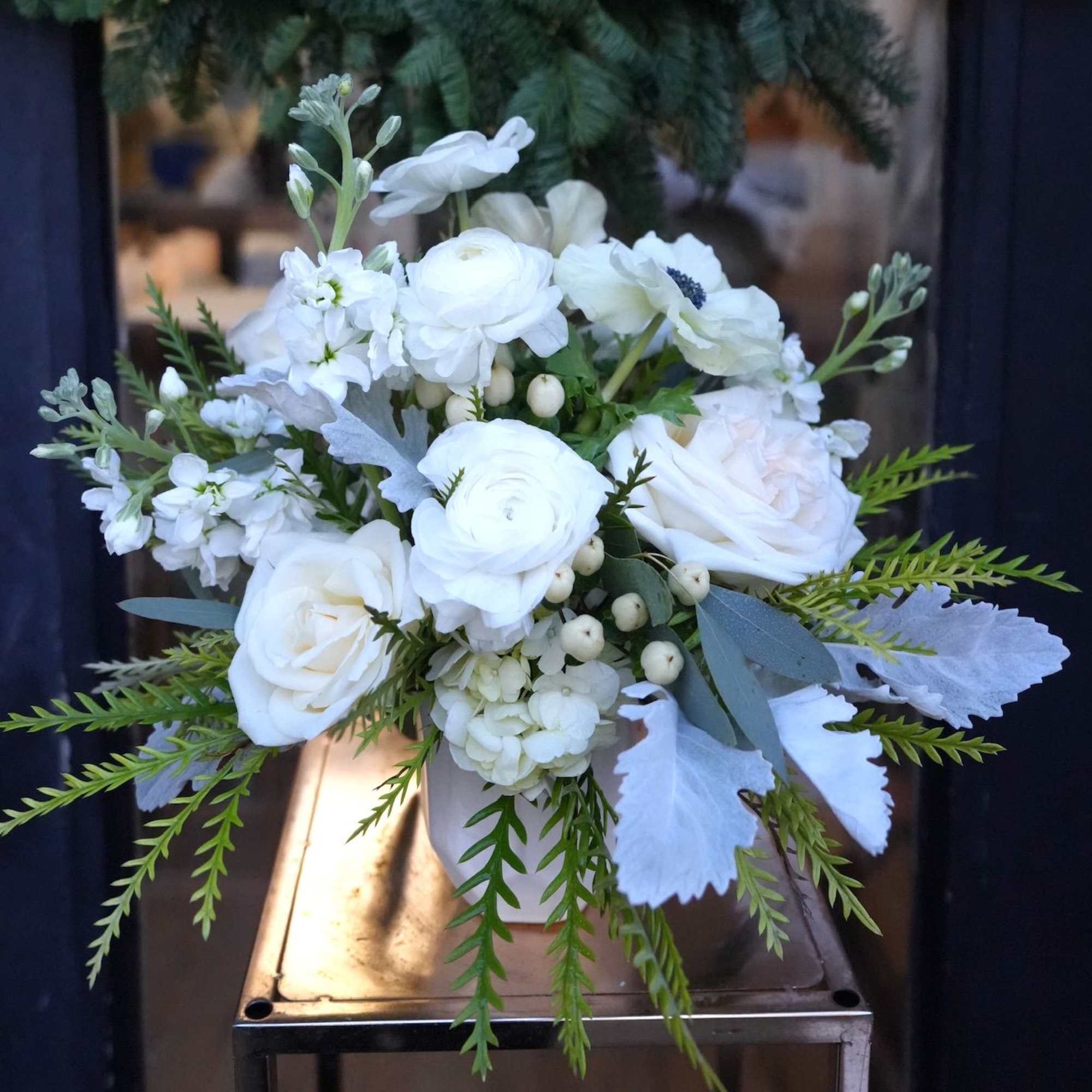 White floral bouquet in a small vase with trailing greenery