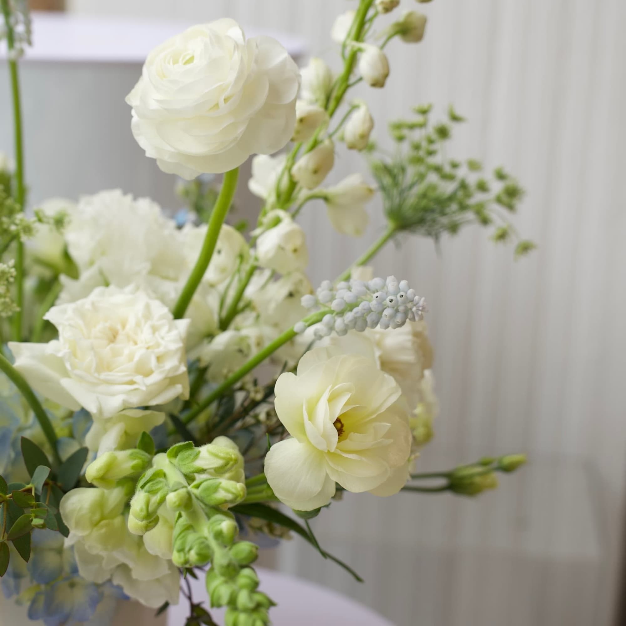 White floral arrangement in a white vase with tall stems and round blooms