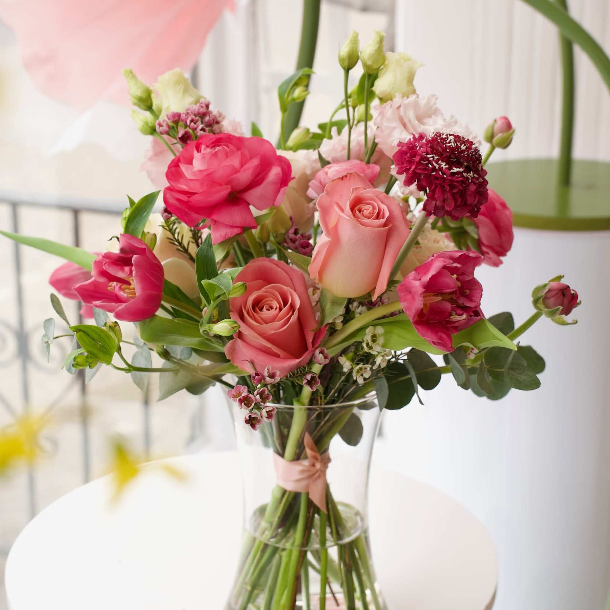 Pink and coral bouquet of roses and tulips in a clear glass vase