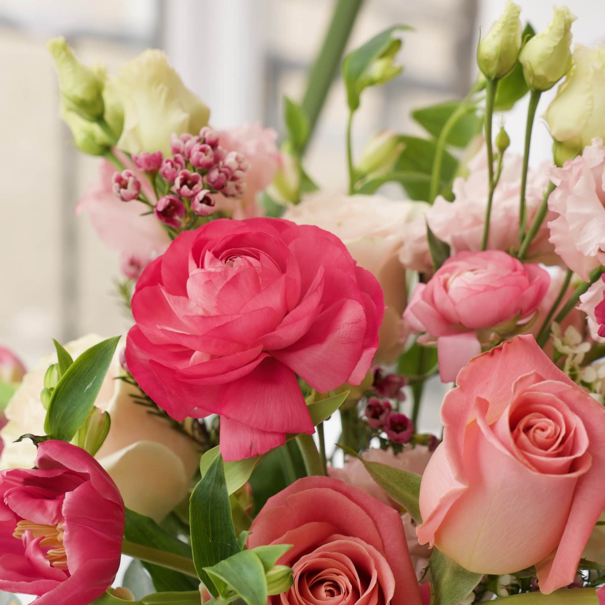 Pink and peach roses with ranunculus and small blossoms in a bouquet