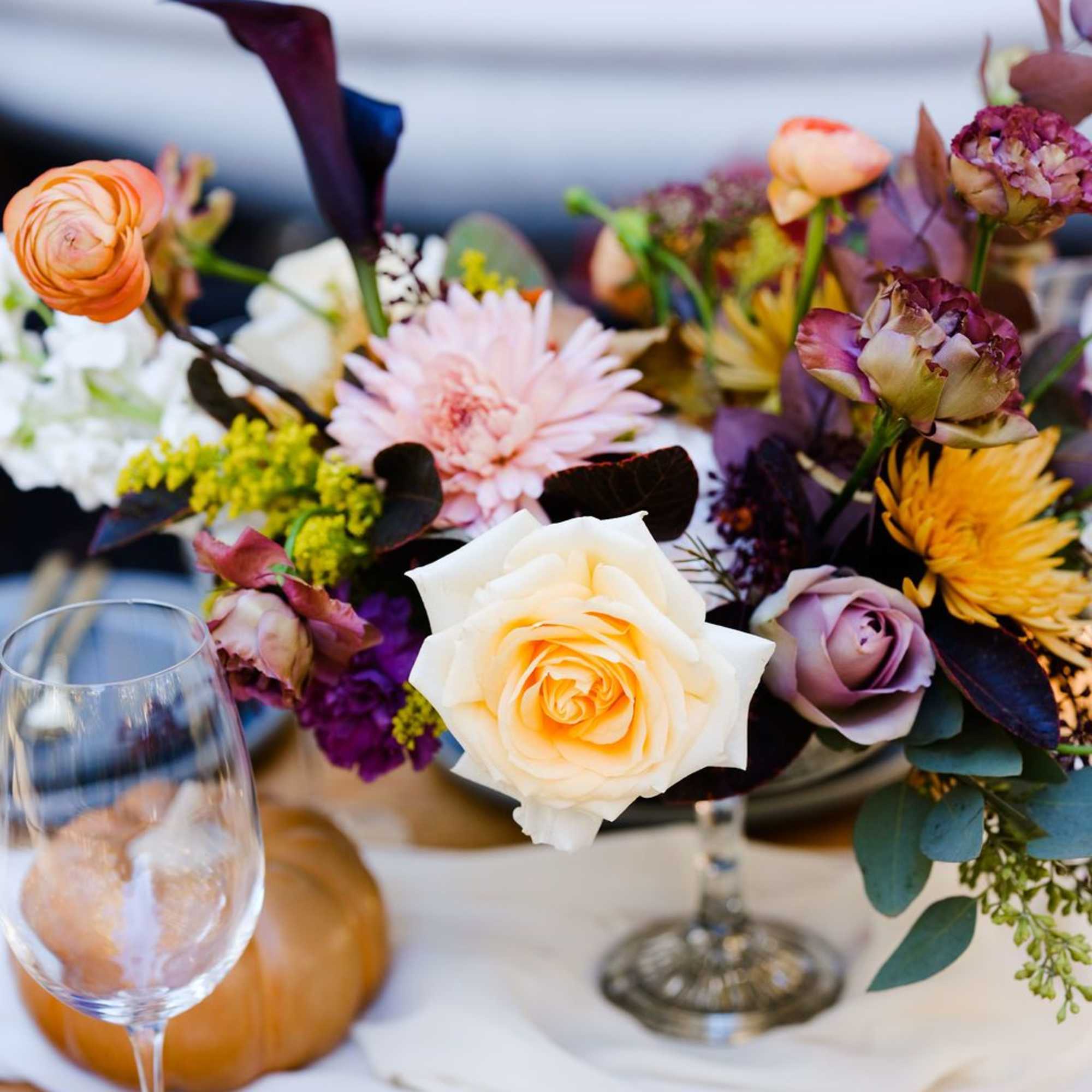 Mixed floral centerpiece with roses, calla lilies, and chrysanthemums in a low vase