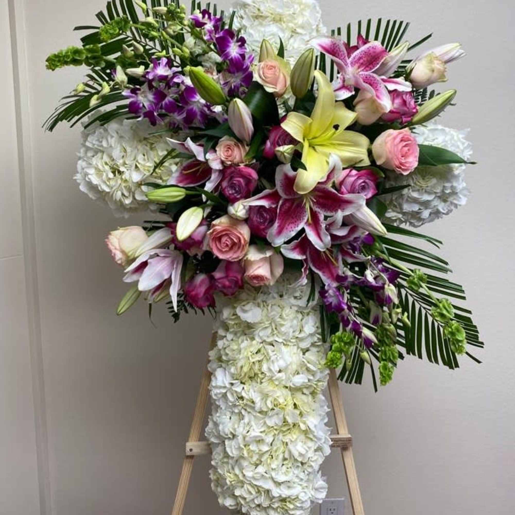 Large floral standing spray with lilies, roses, orchids, and white hydrangeas