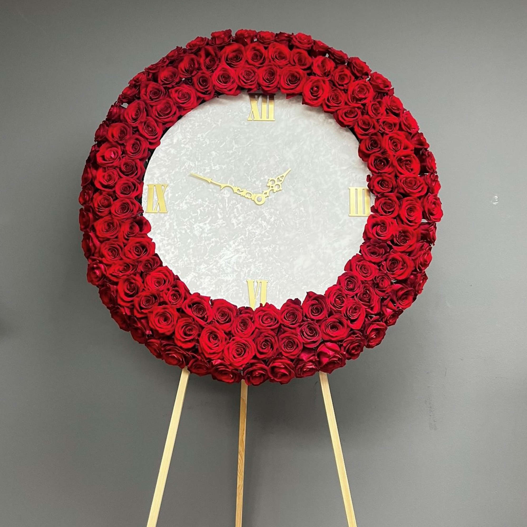 Large circular rose arrangement on an easel with clock face details