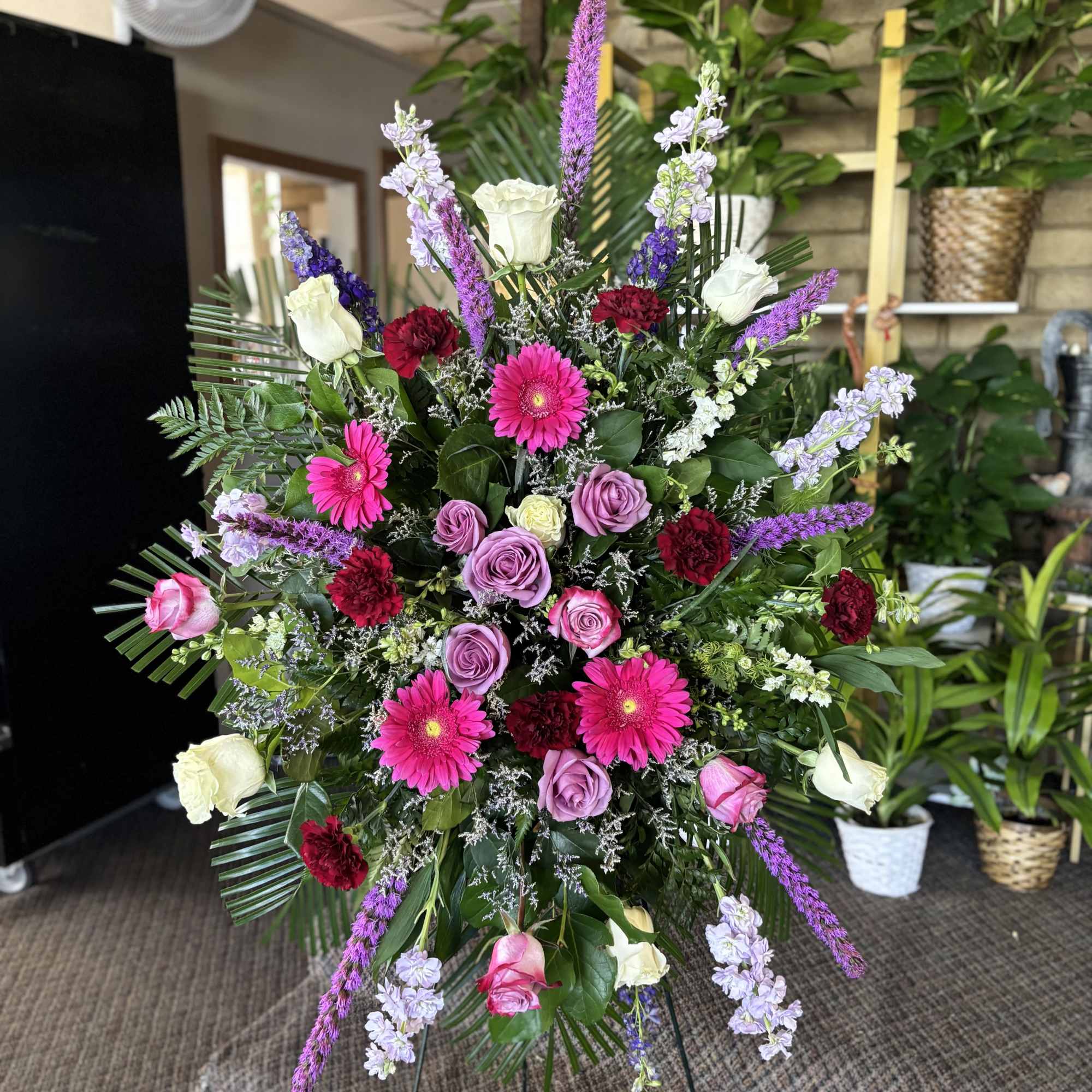 Large standing floral spray with pink, purple, white, and red blooms