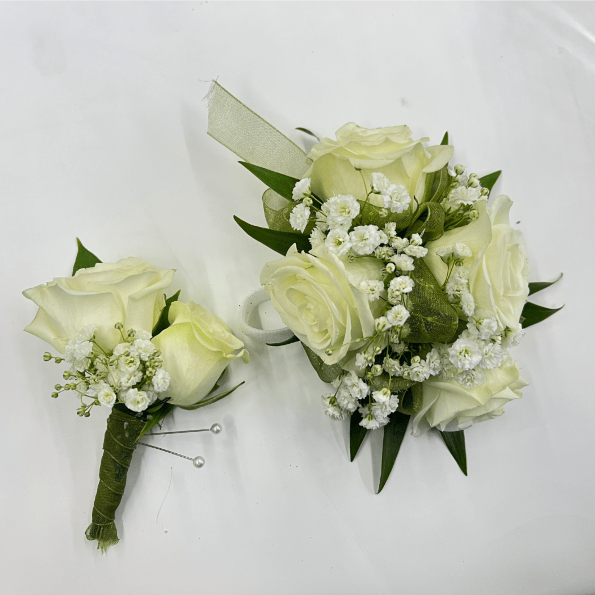 White rose corsage and boutonniere set accented with baby&rsquo;s breath for a